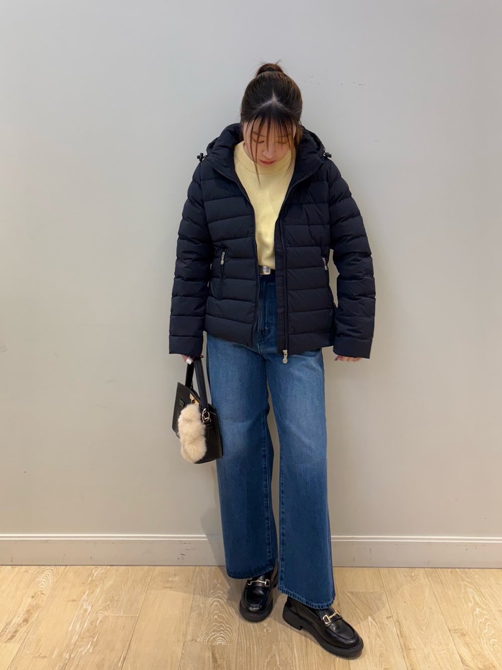 イエロー系のニット/セーター、ブルー系のデニムパンツ、ブラック系のショルダーバッグを着用したレディースの秋コーディネートの1枚目の写真