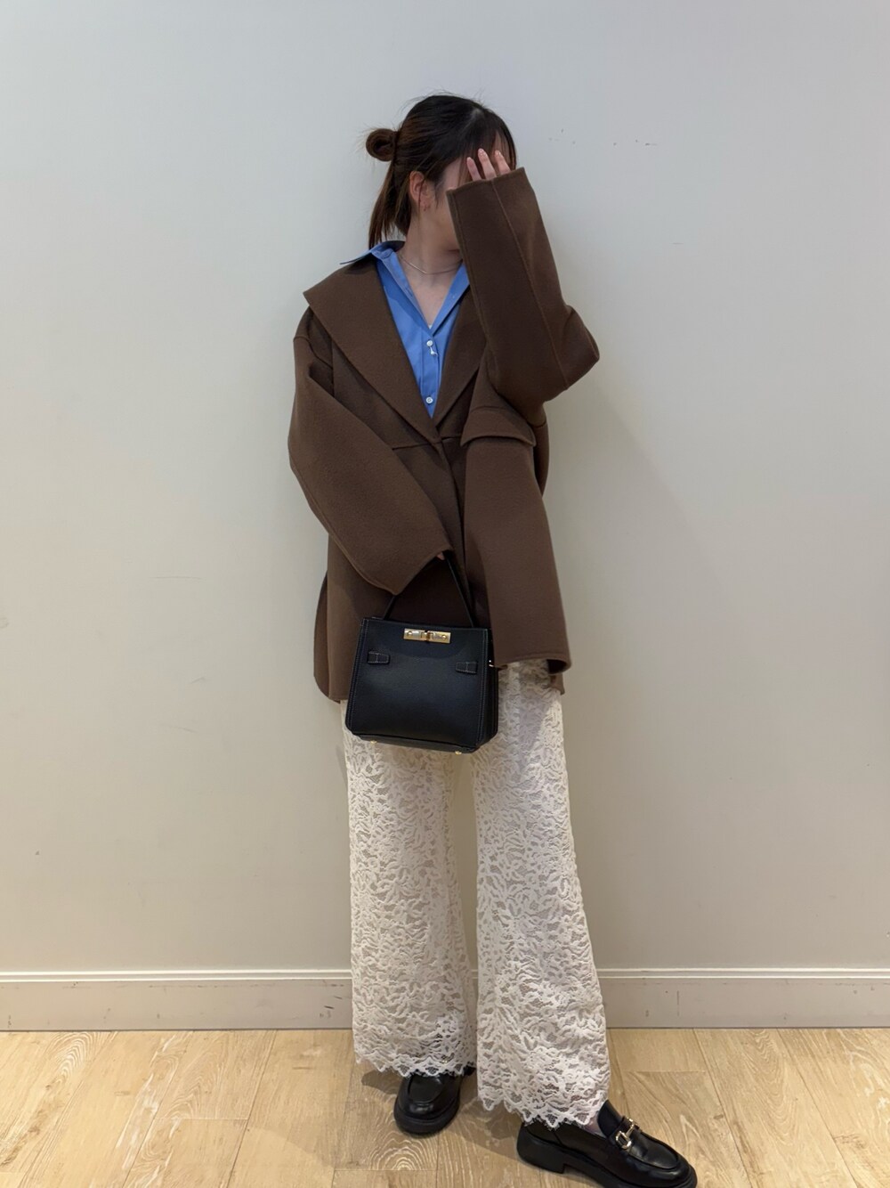 ブラック系のショルダーバッグ、ブラウン系のその他アウター、ブルー系のシャツ/ブラウスを着用したレディースの冬コーディネートの1枚目の写真