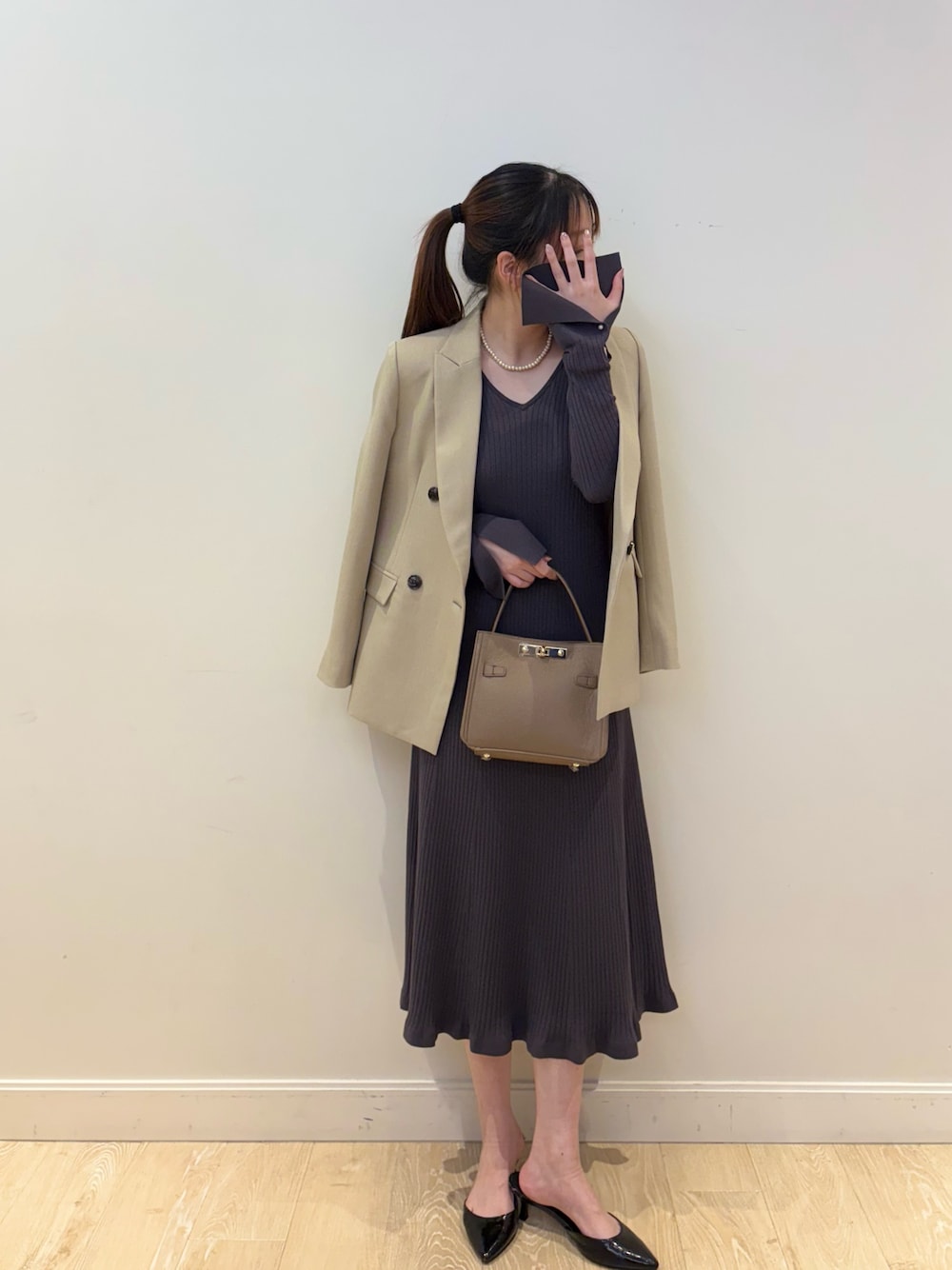 ベージュ系のショルダーバッグ、グレー系のワンピース、ベージュ系のテーラードジャケットを着用したレディースの冬コーディネートの1枚目の写真