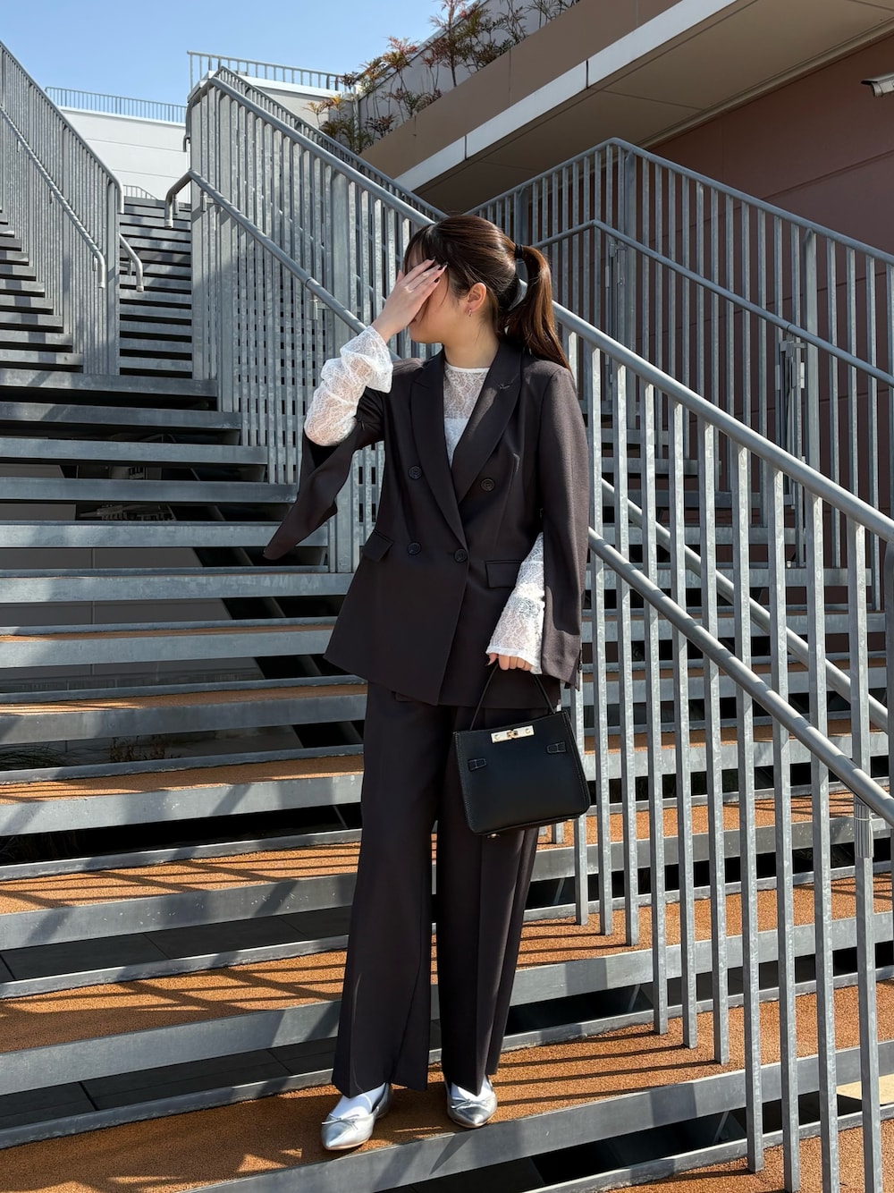 ブラック系のショルダーバッグ、ブラック系のTシャツ/カットソー、グレー系のテーラードジャケットを着用したレディースの冬コーディネートの1枚目の写真