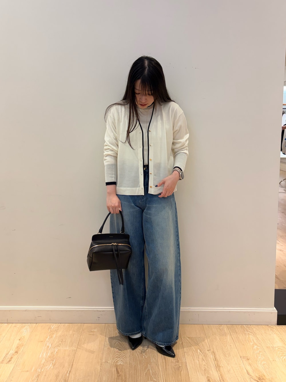 ブラック系のショルダーバッグ、ブルー系のデニムパンツ、ホワイト系のニット/セーターを着用したレディースの秋コーディネートの1枚目の写真