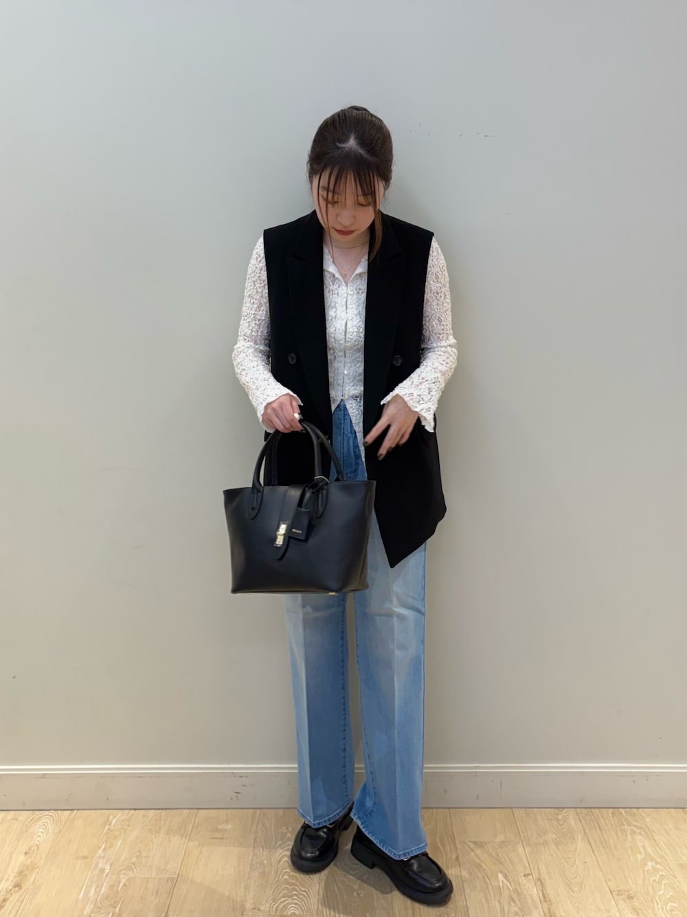 ブラック系のトートバッグ、ブルー系のデニムパンツ、ホワイト系のカーディガン/ボレロを着用したレディースの冬コーディネートの1枚目の写真