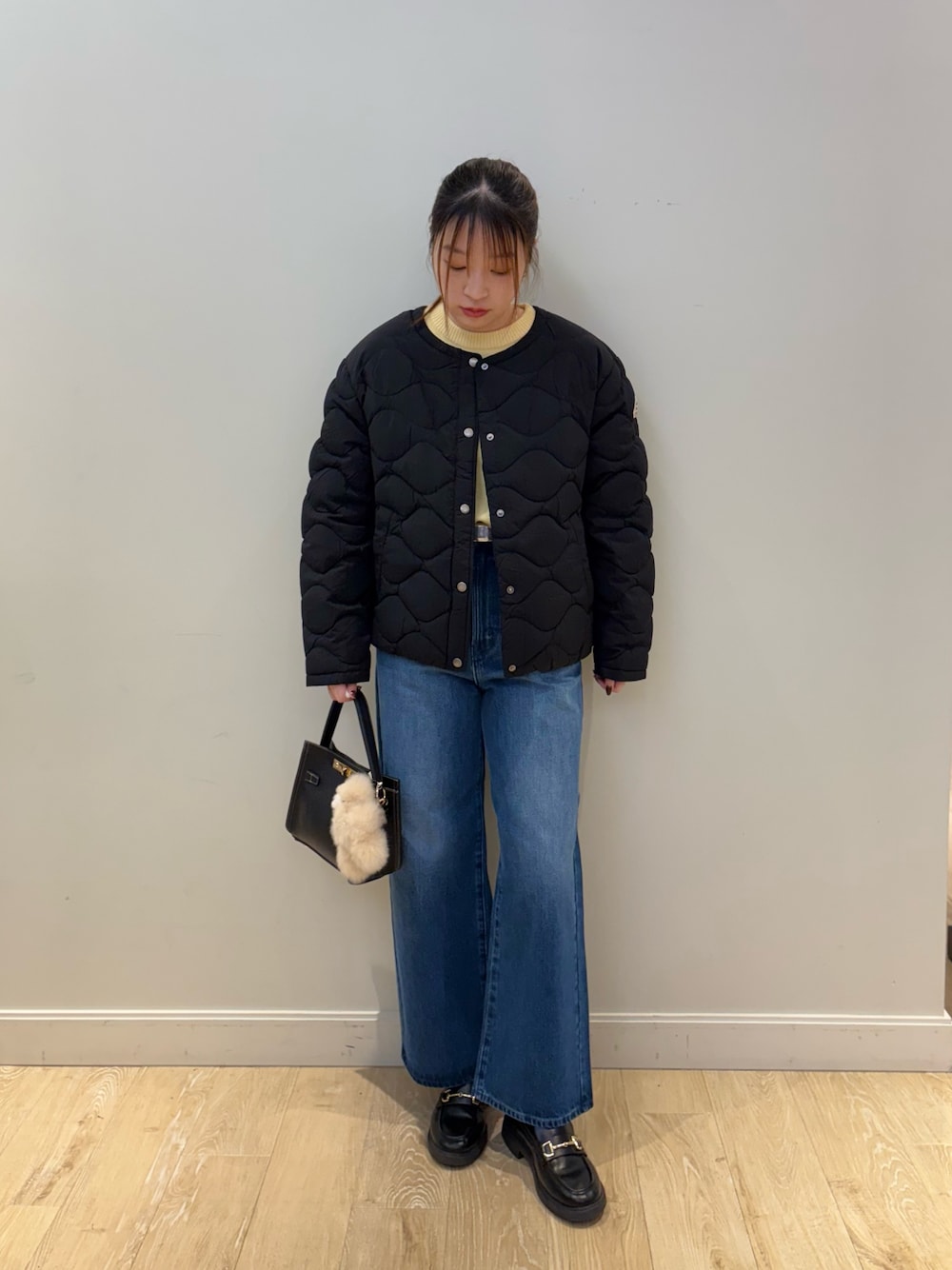 イエロー系のニット/セーター、ブルー系のデニムパンツ、ブラック系のショルダーバッグを着用したレディースの秋コーディネートの1枚目の写真