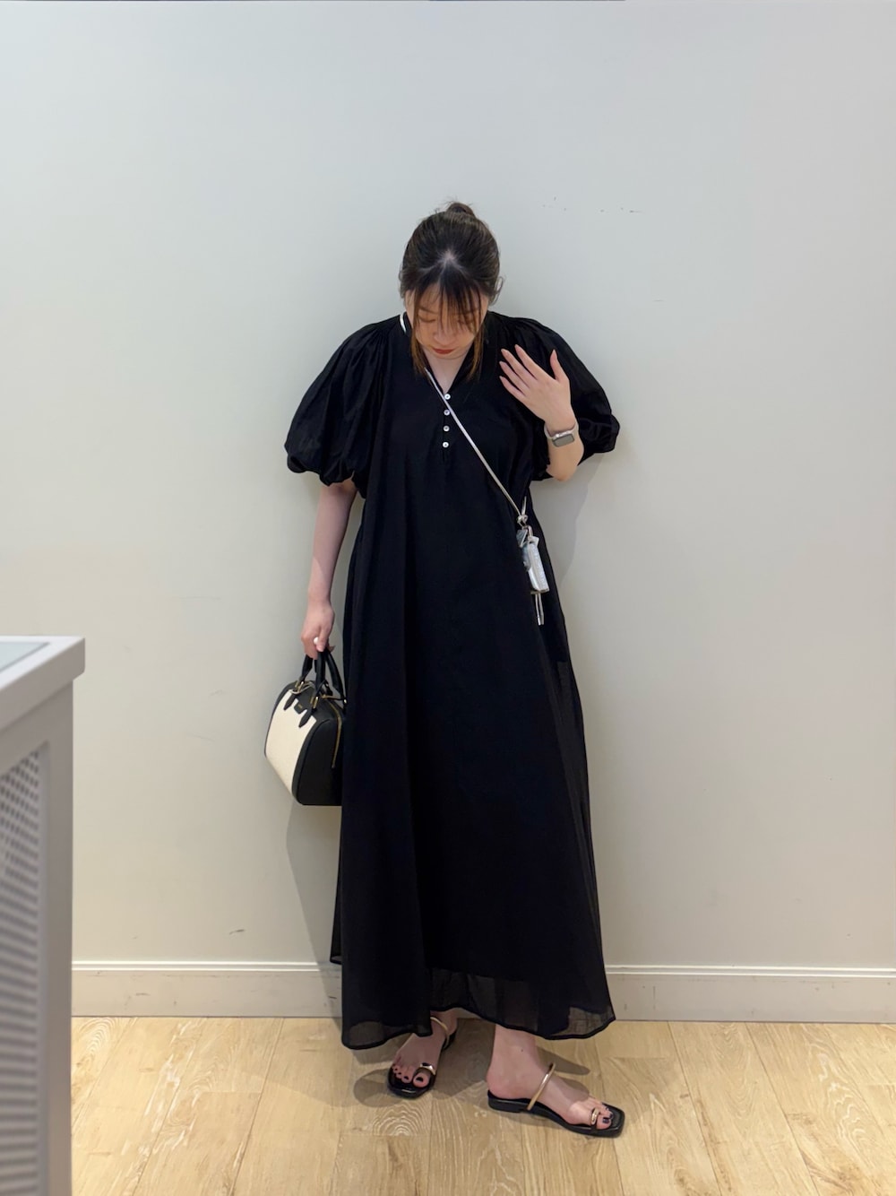 ブラック系のボストンバッグ、ブラック系のワンピース、シルバー系のチャームを着用したレディースの夏コーディネートの1枚目の写真