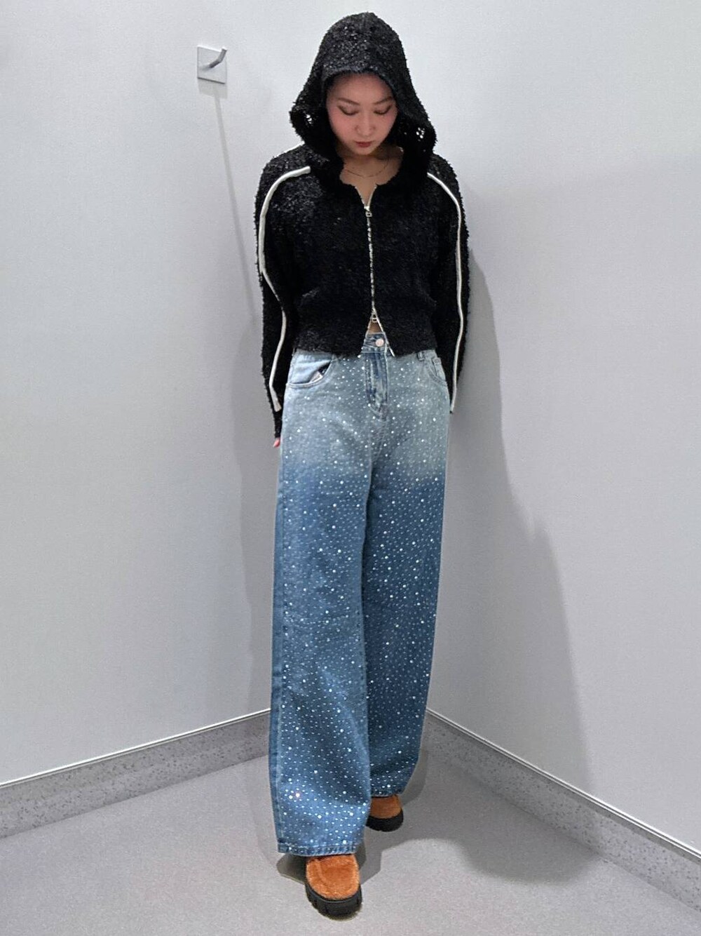 ブルー系のデニムパンツ、ブラック系のカーディガン/ボレロ、ブラウン系のローファーを着用したレディースの冬コーディネートの1枚目の写真