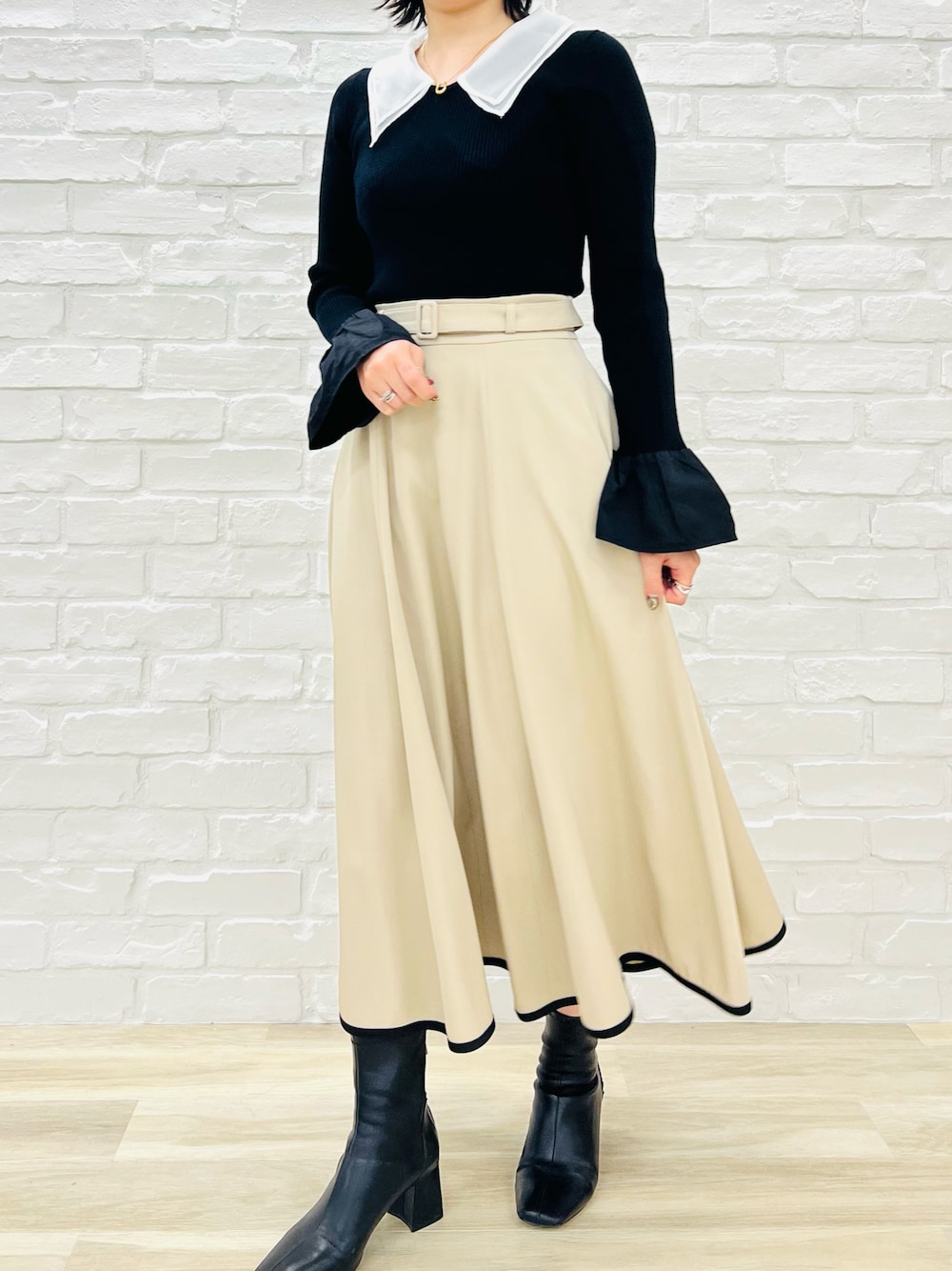 ブラック系のニット/セーター、ベージュ系のスカートを着用したレディースの冬コーディネートの1枚目の写真