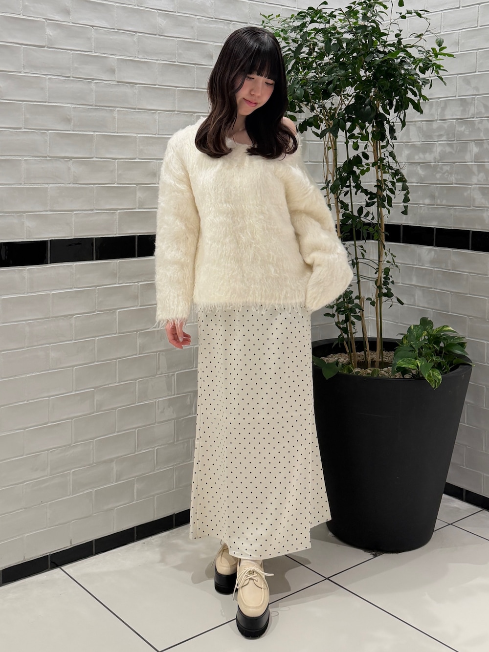 ホワイト系のニット/セーター、ホワイト系のスカート、ホワイト系のローファーを着用したレディースの秋コーディネートの1枚目の写真