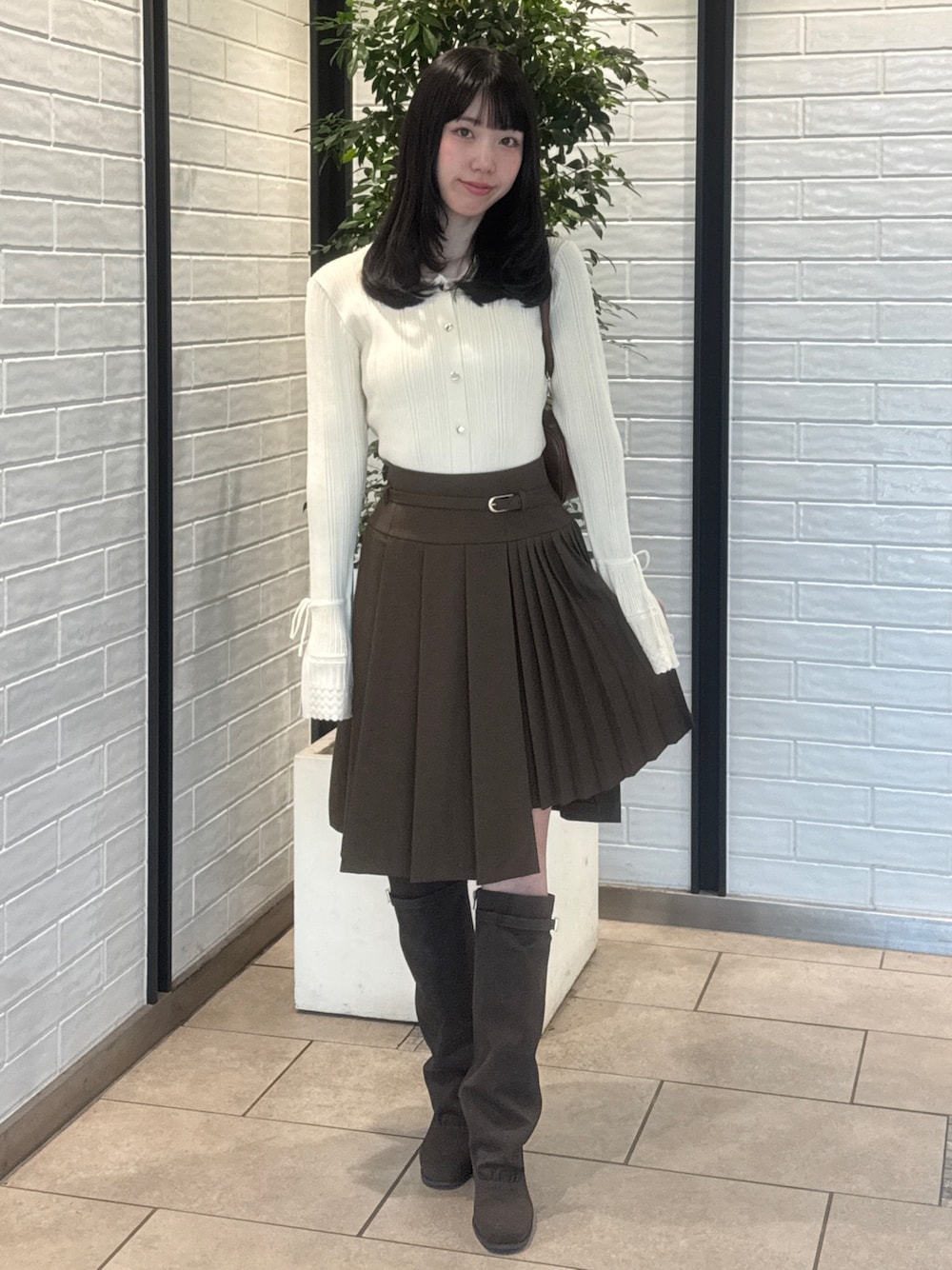 ホワイト系のニット/セーター、ブラウン系のスカート、ブラウン系のブーツを着用したレディースの秋コーディネートの1枚目の写真