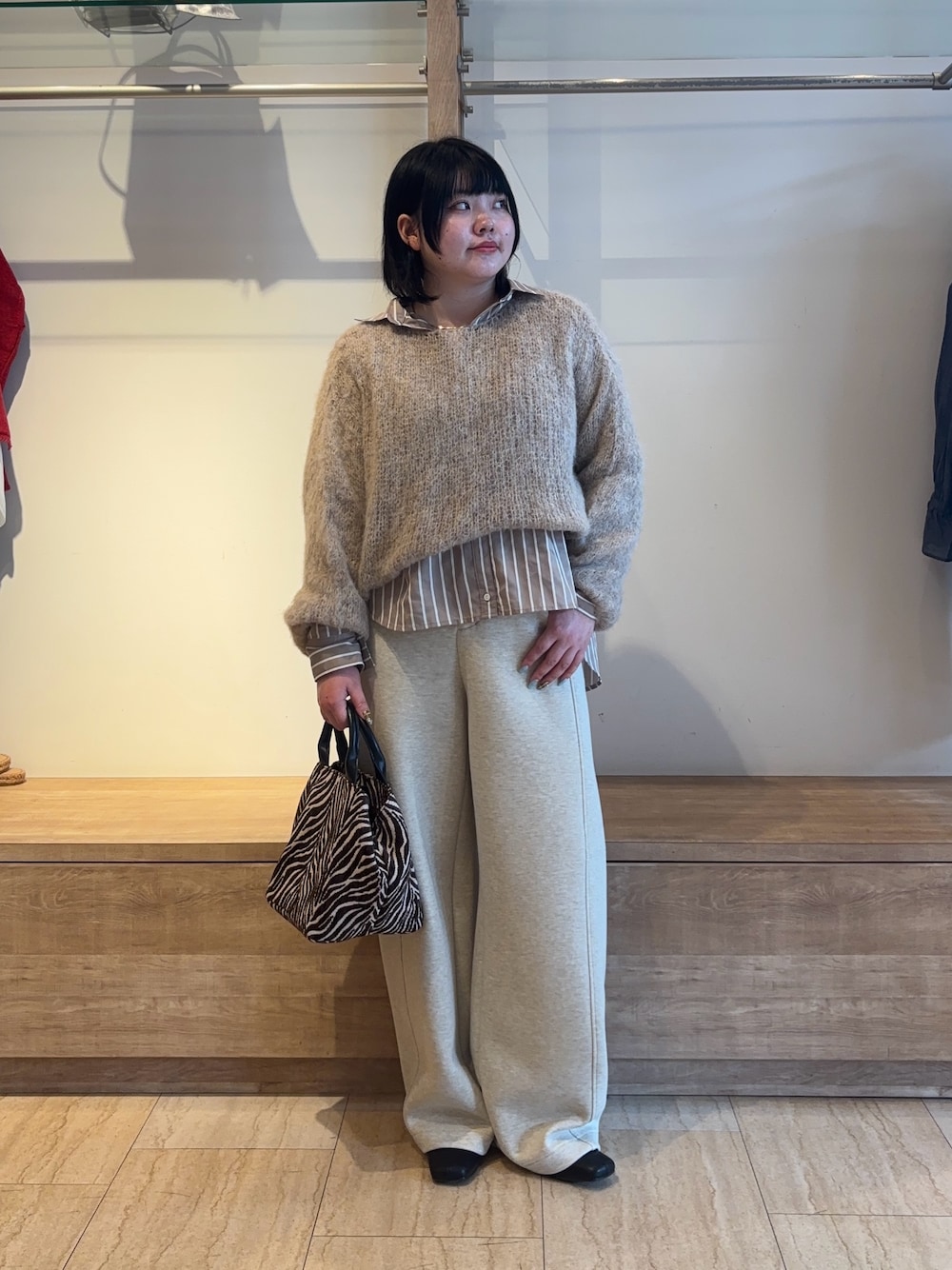 ベージュ系のニット/セーター、ブラウン系のシャツ/ブラウス、ブラウン系のトートバッグを着用したレディースの秋コーディネートの1枚目の写真