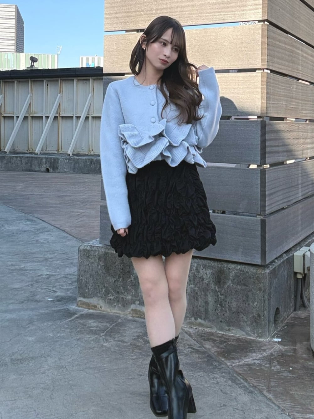 ブルー系のノーカラージャケット、ブラック系のスカート、ブラック系のブーツを着用したレディースの冬コーディネートの1枚目の写真