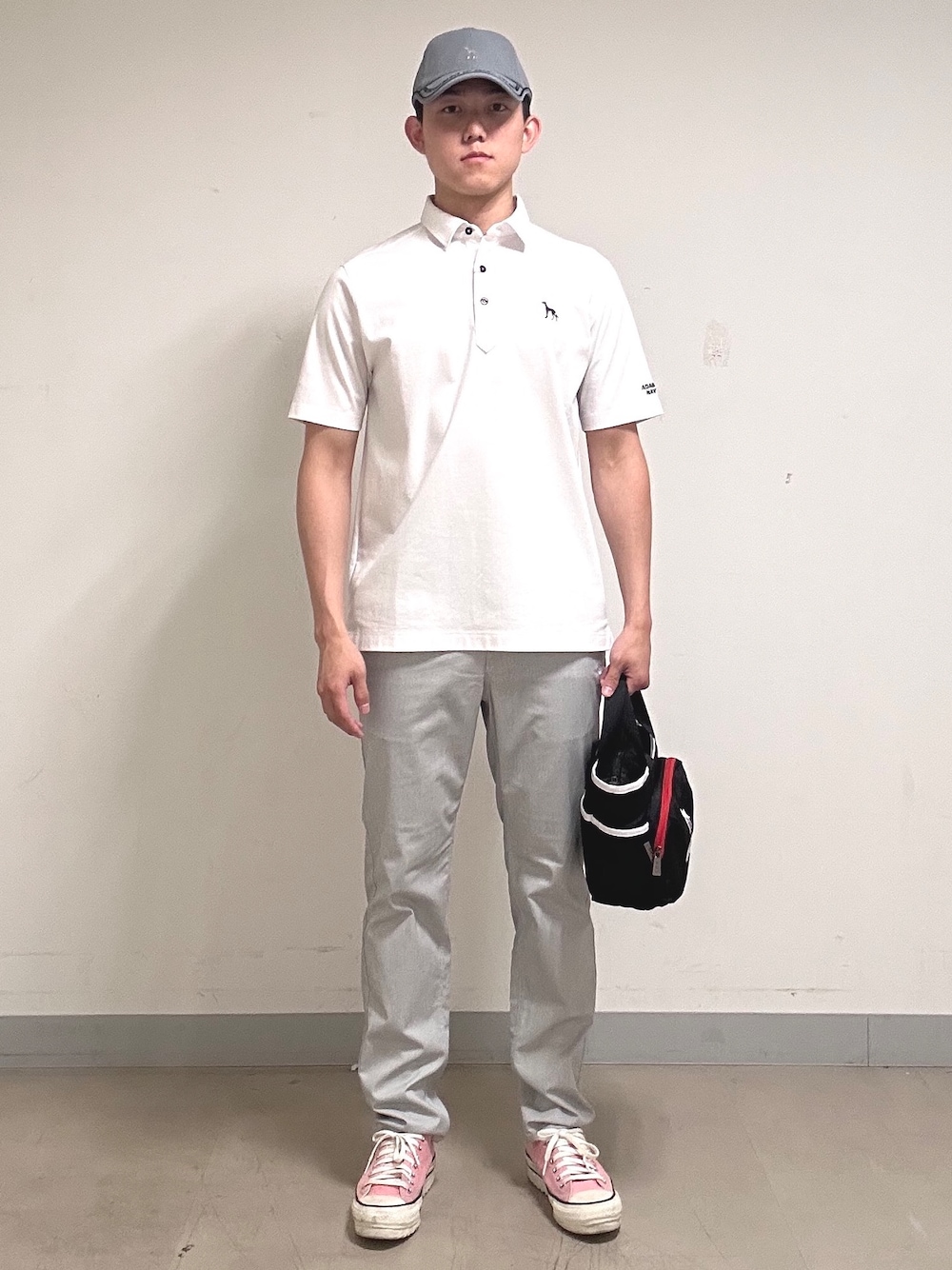 ホワイト系のポロシャツ、グレー系のその他パンツ、ブラック系のトートバッグを着用したメンズの夏コーディネートの1枚目の写真