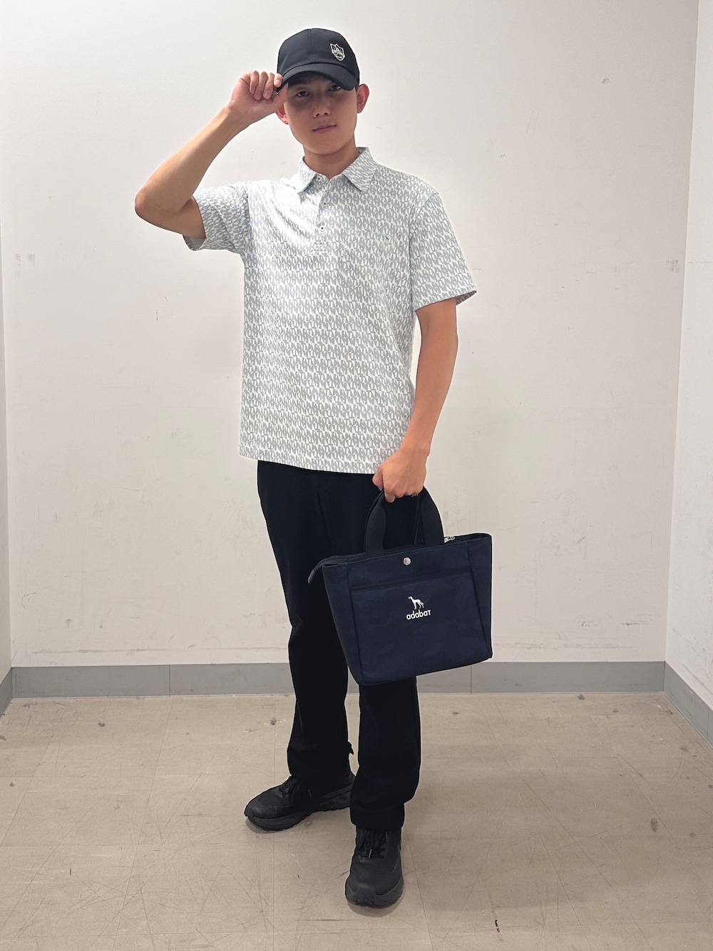 グレー系のポロシャツ、ブラック系のその他パンツ、ブルー系のトートバッグを着用したメンズの夏コーディネートの1枚目の写真