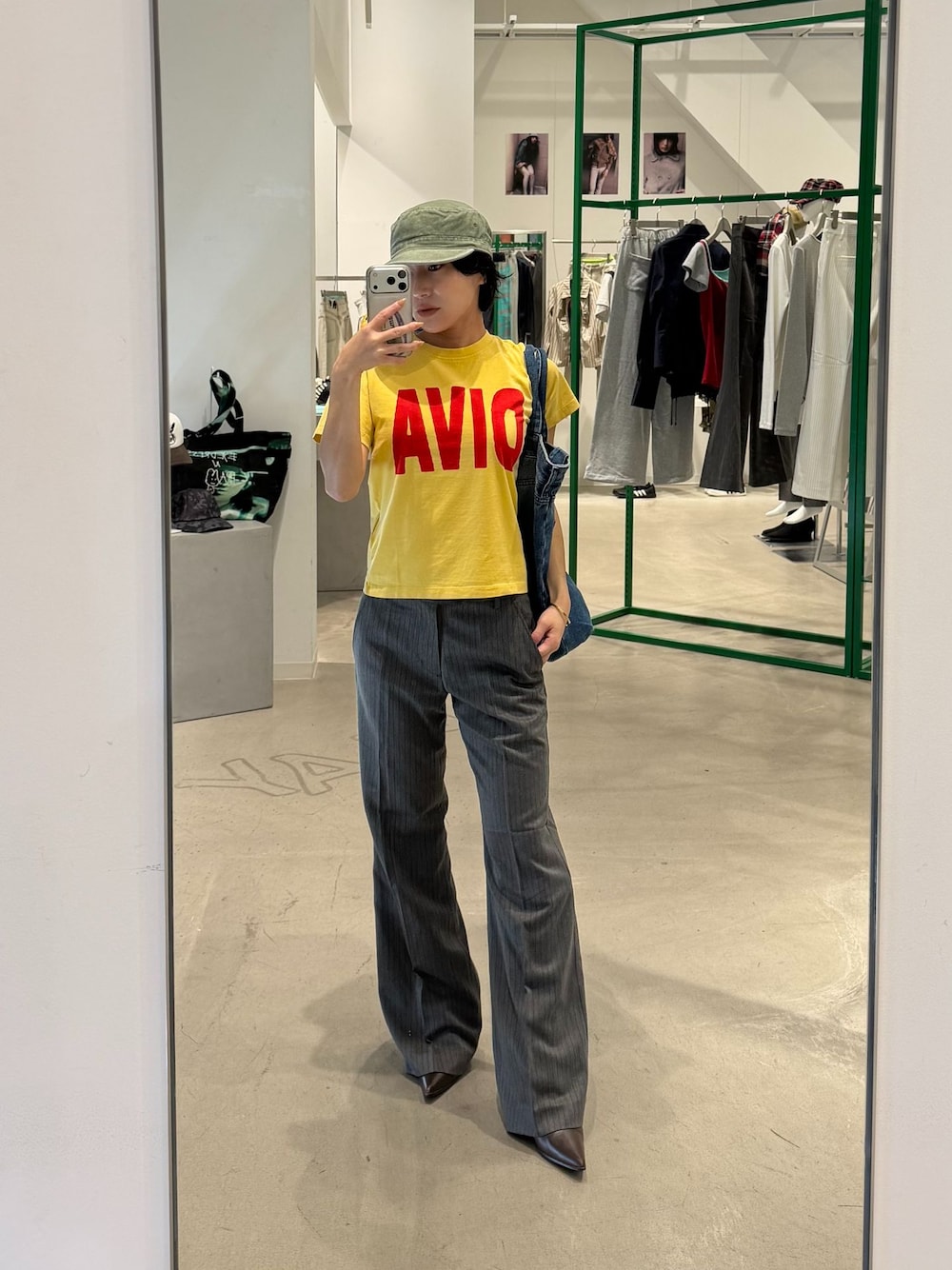 グレー系のスラックス、イエロー系のTシャツ/カットソー、ブルー系のトートバッグを着用したレディースの秋コーディネートの1枚目の写真