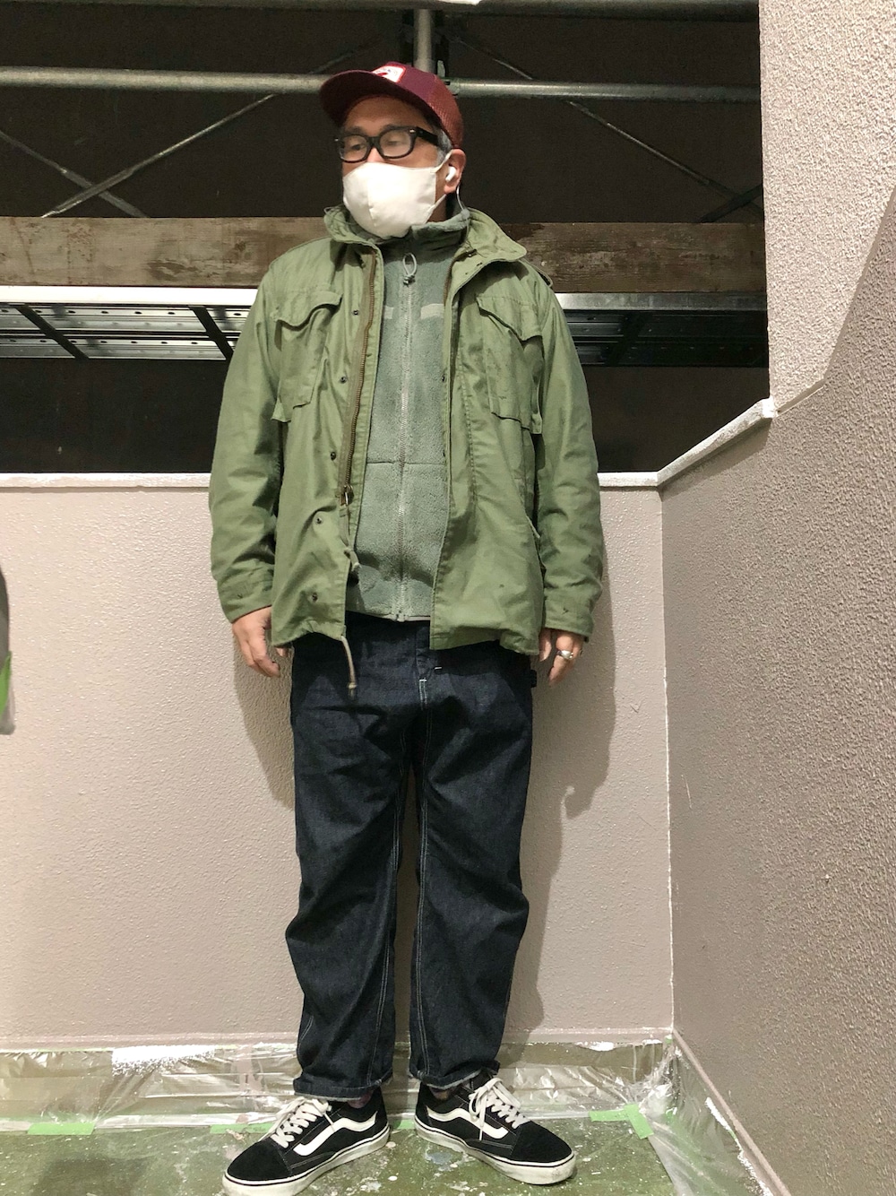 ブルー系のデニムパンツ、ブラック系のスニーカー、グリーン系のテーラードジャケットを着用したメンズの冬コーディネートの1枚目の写真