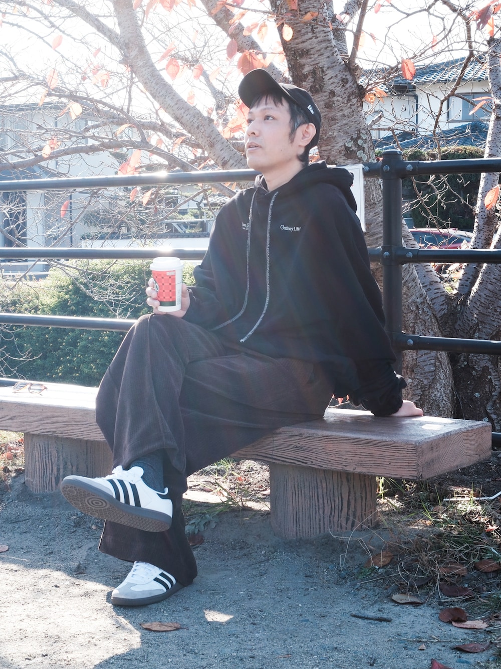 ブラウン系のスラックス、ホワイト系のスニーカー、ブラック系のパーカーを着用したメンズの秋コーディネートの1枚目の写真