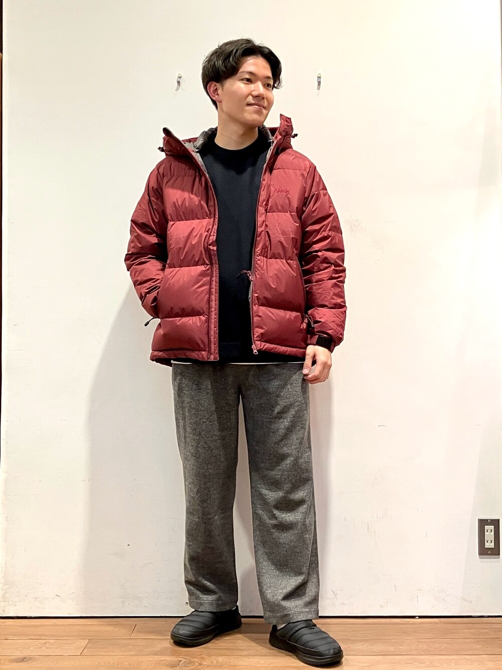 レッド系のダウンジャケット/コート、ブラック系のニット/セーター、グレー系のその他パンツを着用したメンズの秋コーディネートの1枚目の写真