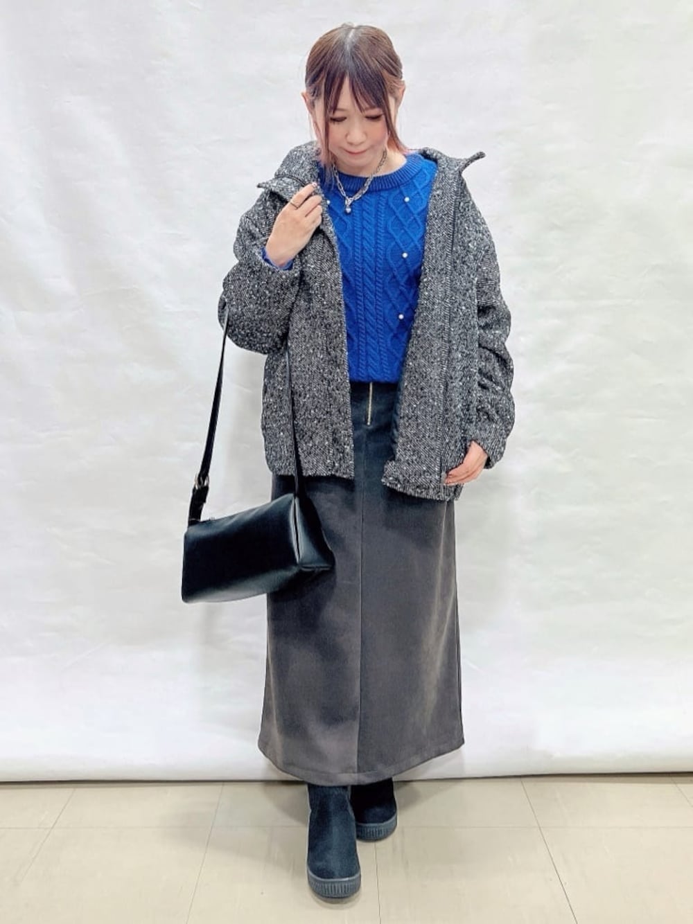 ブラック系のブルゾン、ブルー系のニット/セーター、グレー系のスカートを着用したレディースの冬コーディネートの1枚目の写真