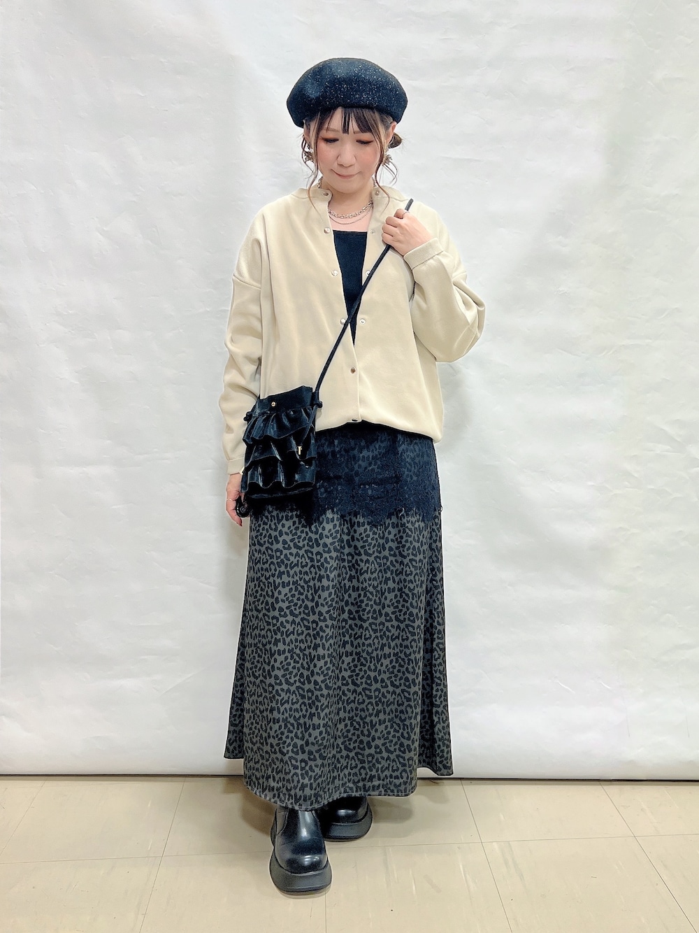 ベージュ系のカーディガン/ボレロ、ブラック系のタンクトップ、グレー系のスカートを着用したレディースの秋コーディネートの1枚目の写真