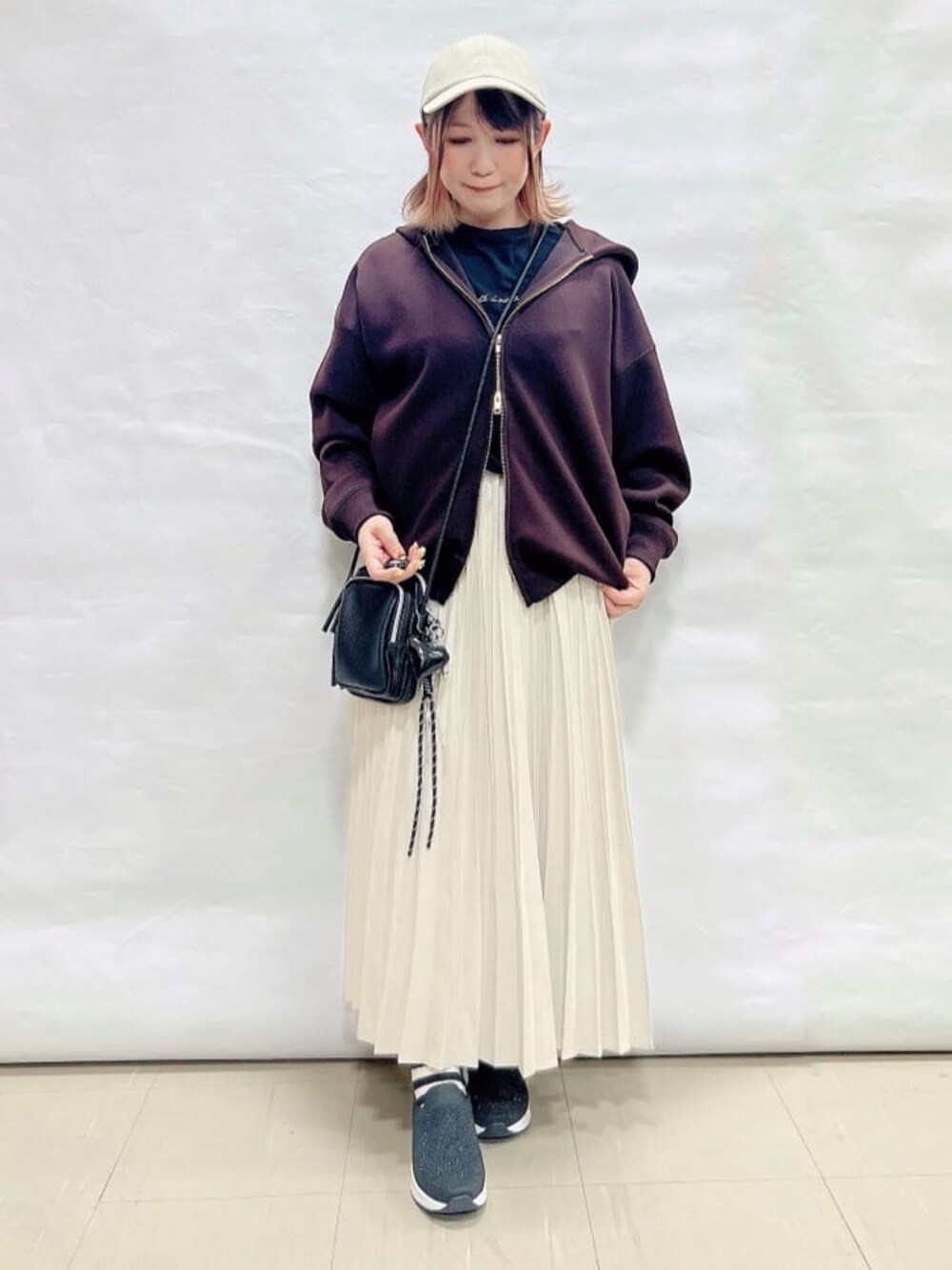 ブラウン系のパーカー、ブラック系のTシャツ/カットソー、ホワイト系のスカートを着用したレディースの春コーディネートの1枚目の写真