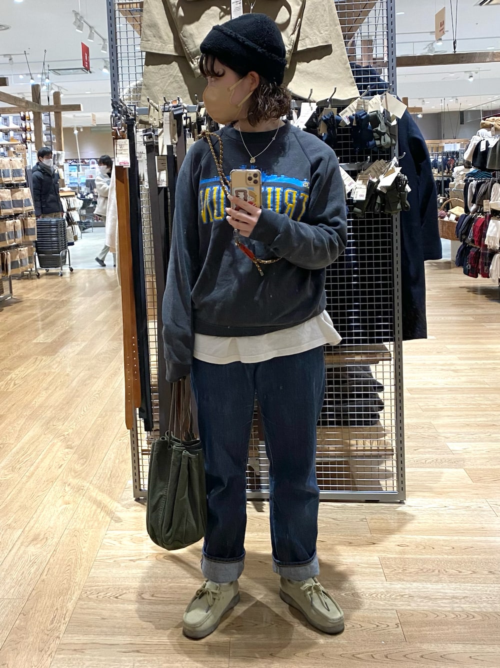 グリーン系のハンドバッグ、ベージュ系のモカシン/デッキシューズ、ブルー系のデニムパンツを着用したレディースの冬コーディネートの1枚目の写真