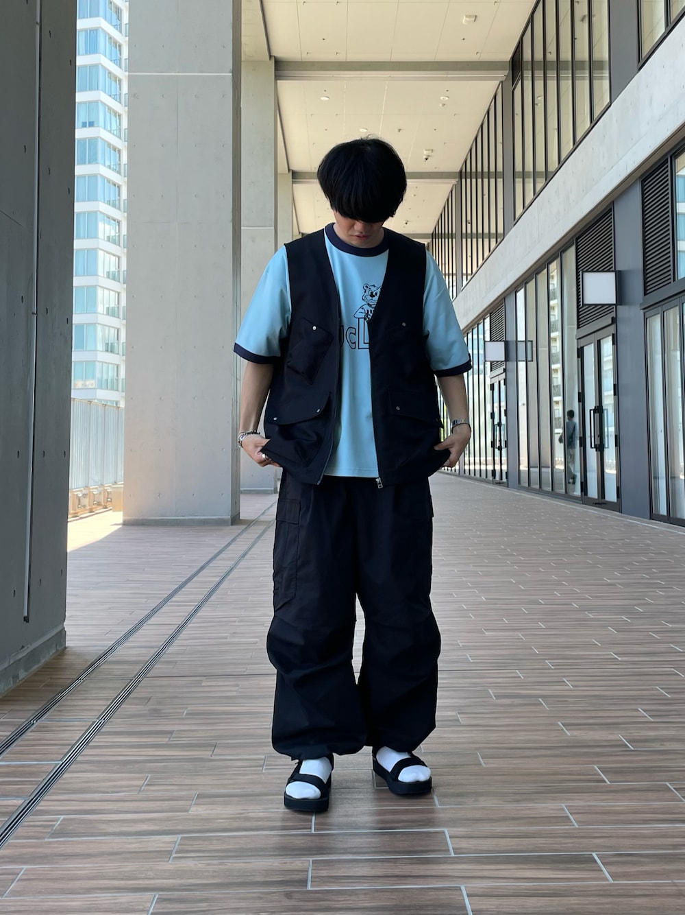 ブルー系のTシャツ/カットソー、ブラック系のベスト、ブラック系のサンダルを着用したメンズの夏コーディネートの1枚目の写真