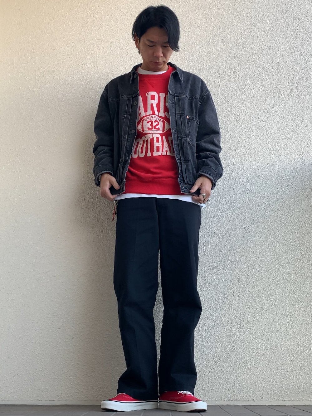 ブラック系のデニムジャケット、ブラック系のチノパンツ、レッド系のスニーカーを着用したメンズの冬コーディネートの1枚目の写真