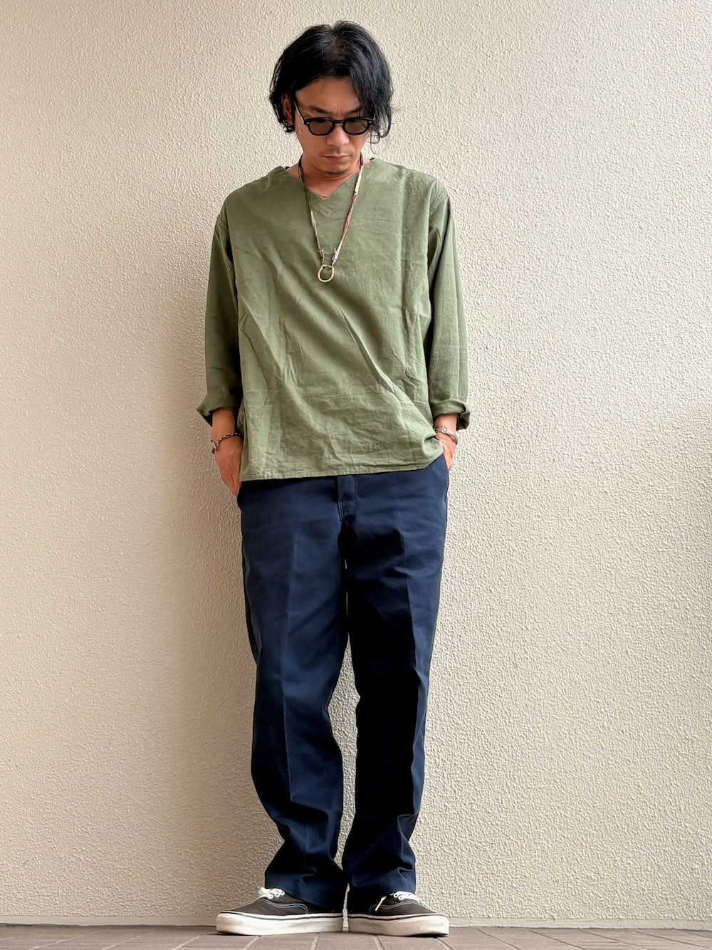 グリーン系のチノパンツ、グリーン系のTシャツ/カットソー、ブラック系のスニーカーを着用したメンズの秋コーディネートの1枚目の写真