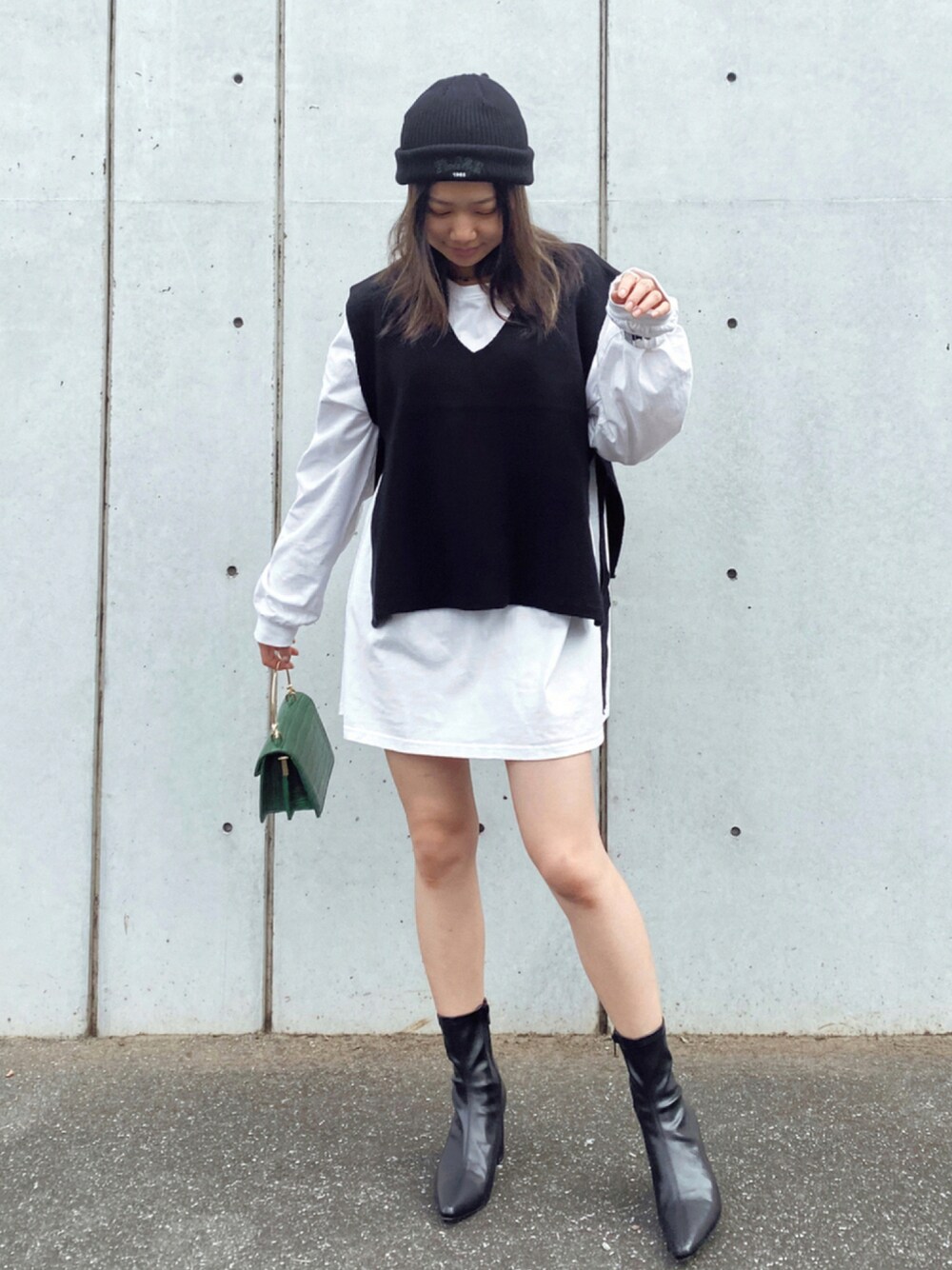 ブラック系のベスト、ホワイト系のTシャツ/カットソー、グリーン系のハンドバッグを着用したレディースの秋コーディネートの1枚目の写真