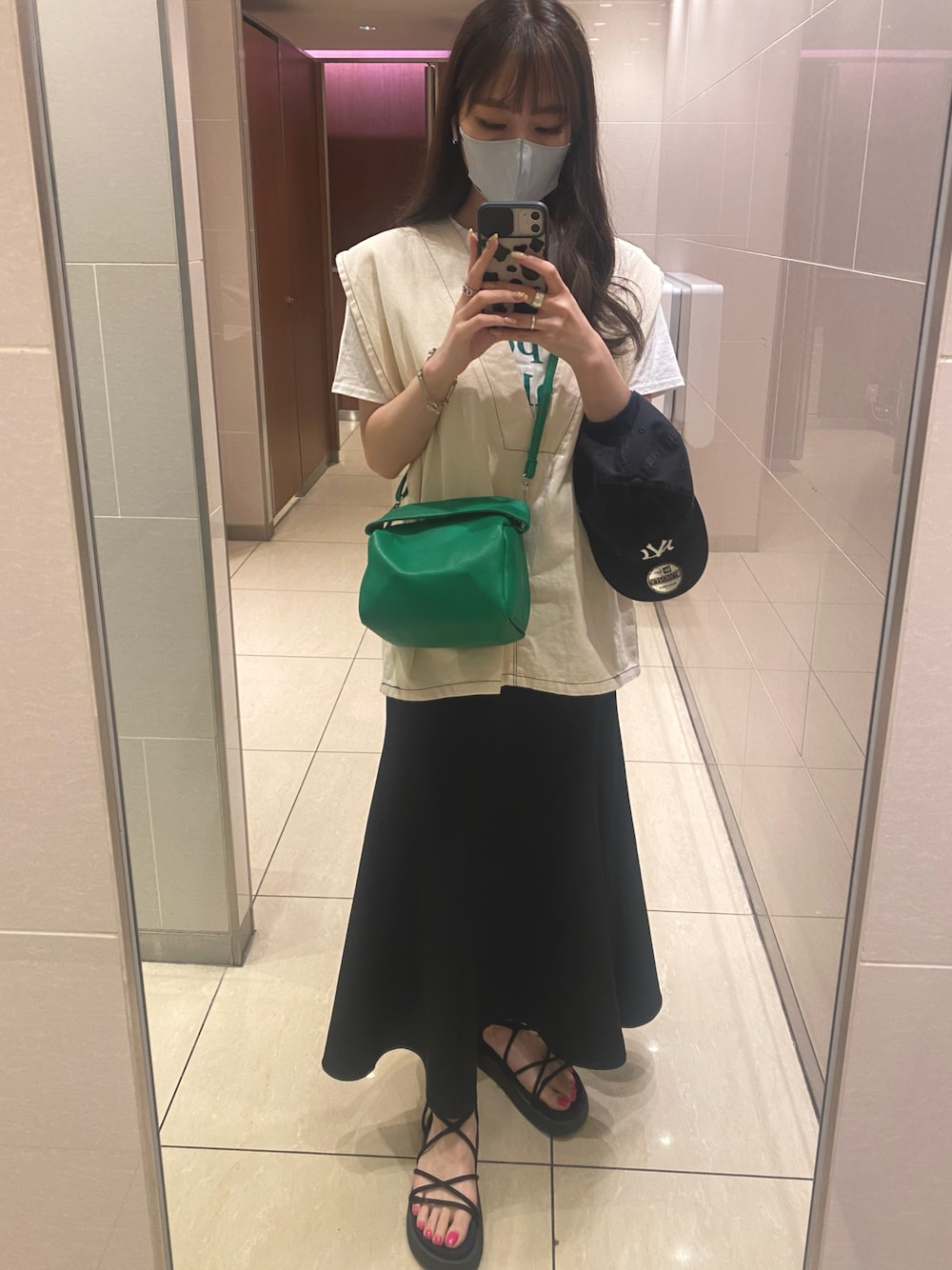 ブラック系のサンダル、ブラック系のスカート、ベージュ系のベストを着用したレディースの夏コーディネートの1枚目の写真