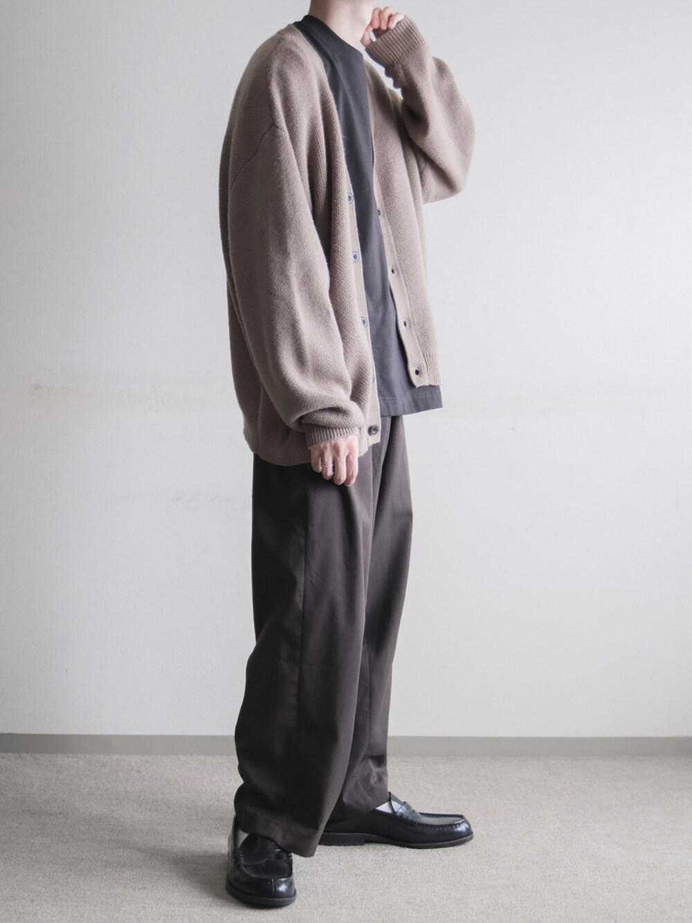 ブラウン系のスラックス、ブラック系のローファー、ブラウン系のカーディガン/ボレロを着用したメンズの秋コーディネートの1枚目の写真