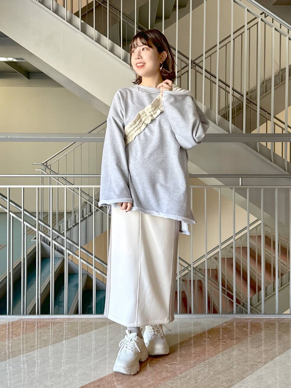 ホワイト系のスカート、グレー系のスウェット、ホワイト系のハンドバッグを着用したレディースの冬コーディネートの1枚目の写真