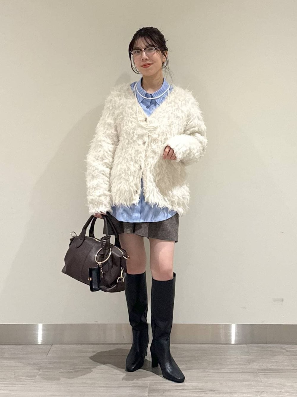 ブラウン系のボストンバッグ、ホワイト系のカーディガン/ボレロ、ブラウン系のその他パンツを着用したレディースの冬コーディネートの1枚目の写真