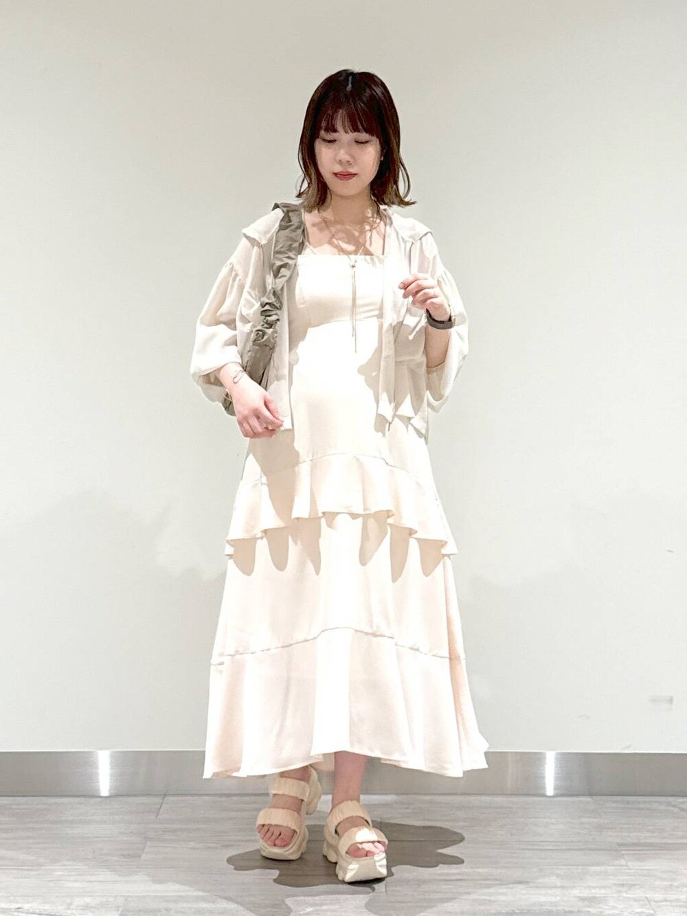 ブラウン系のショルダーバッグ、ベージュ系のキャミソール、ホワイト系のパーカーを着用したレディースの夏コーディネートの1枚目の写真