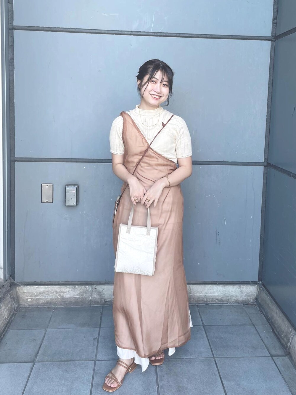 ベージュ系のワンピース、ブラウン系のサンダルを着用したレディースの夏コーディネートの1枚目の写真