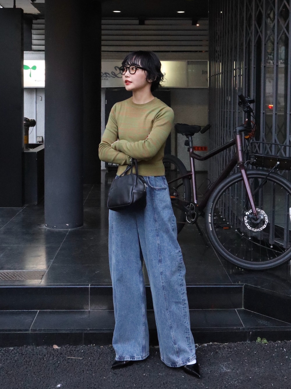 ブルー系のデニムパンツ、ブラック系のパンプス、オレンジ系のニット/セーターを着用したレディースの秋コーディネートの1枚目の写真