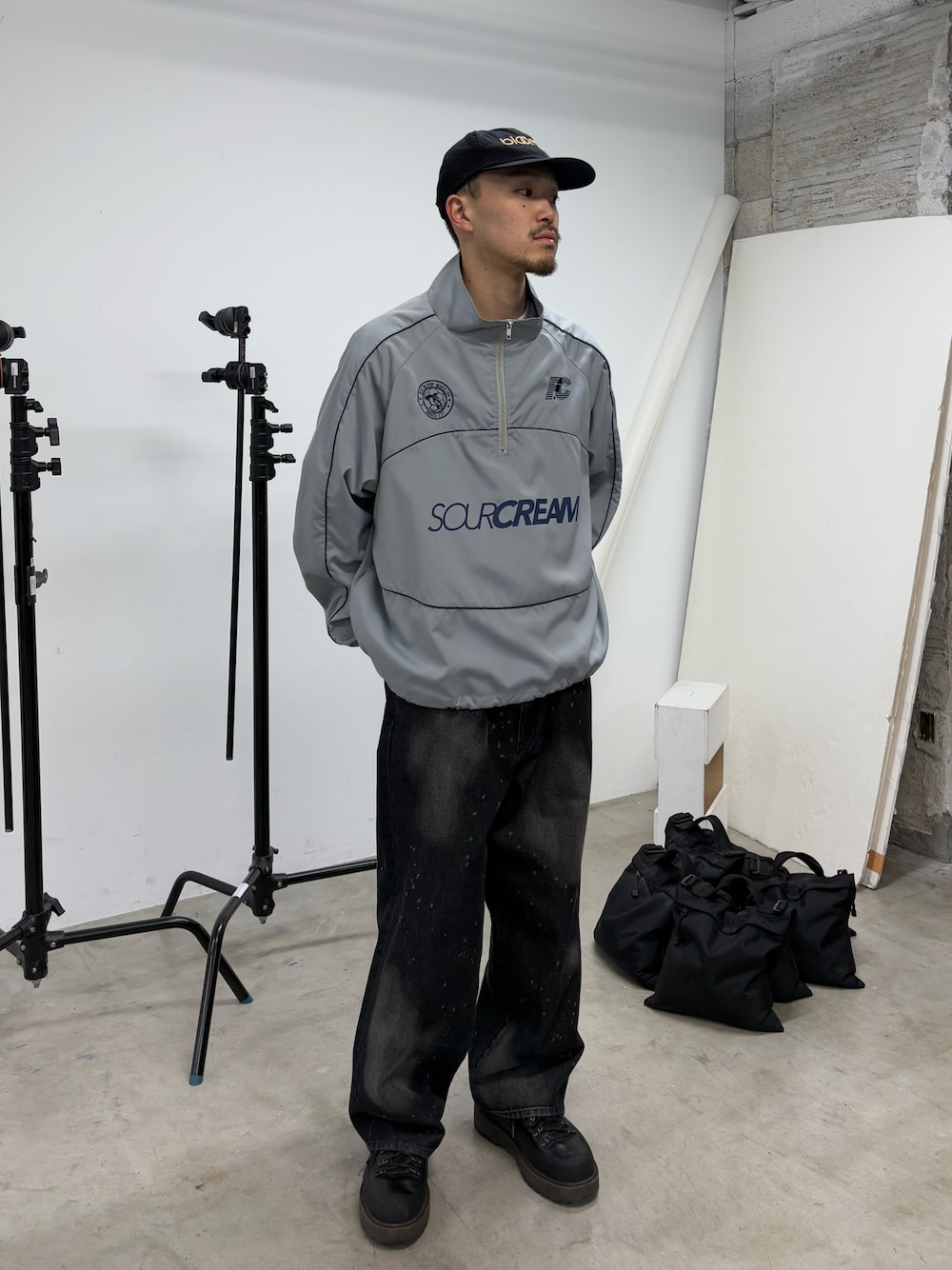 グレー系のナイロンジャケット、ブラック系のデニムパンツを着用したメンズの春コーディネートの1枚目の写真