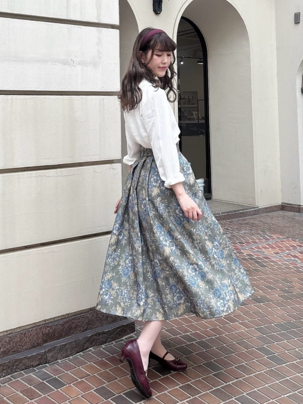 グリーン系のスカート、ホワイト系のシャツ/ブラウス、レッド系のパンプスを着用したレディースの秋コーディネートの1枚目の写真