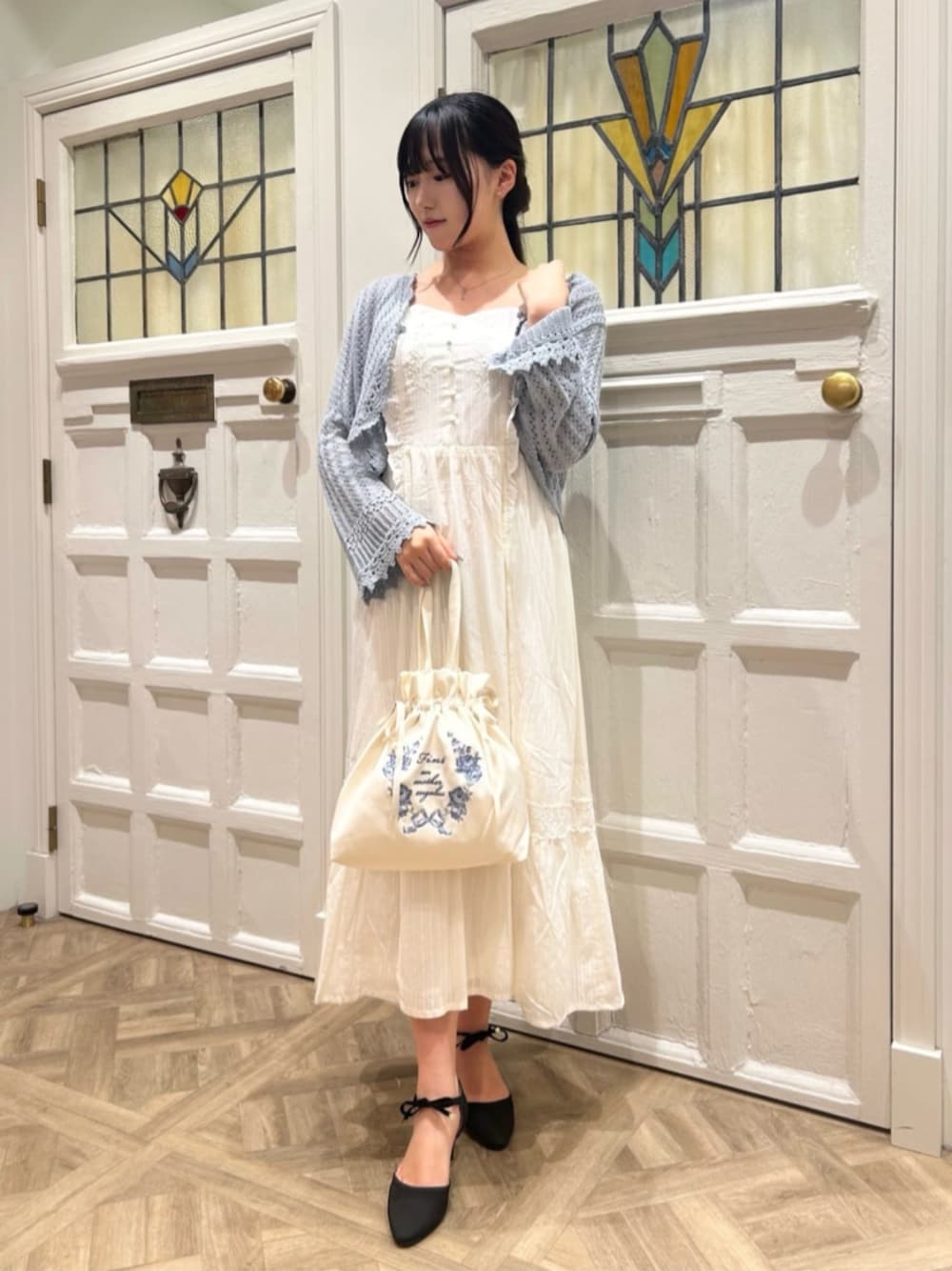 ホワイト系のワンピース、ブルー系のカーディガン/ボレロ、ブラック系のパンプスを着用したレディースの春コーディネートの1枚目の写真