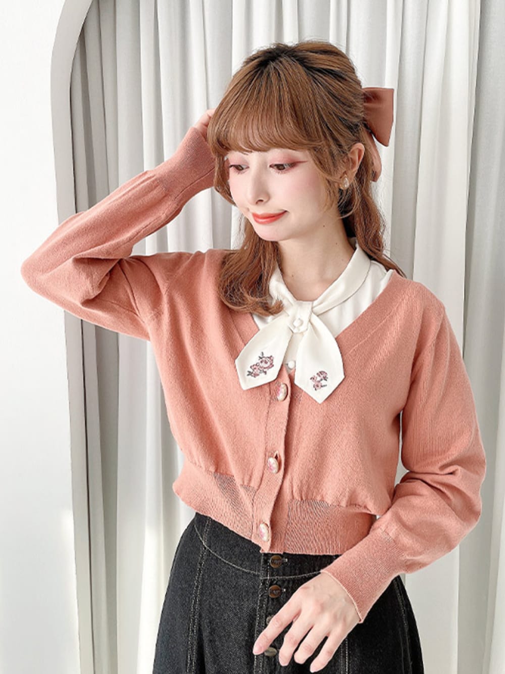 ブラック系のデニムスカート、ブラウン系のバレエシューズ、ピンク系のカーディガン/ボレロを着用したレディースの春コーディネートの1枚目の写真