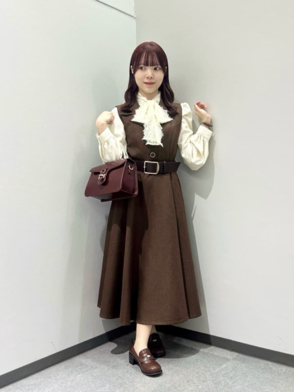 レッド系のハンドバッグ、ブラウン系のローファー、ホワイト系のシャツ/ブラウスを着用したレディースの秋コーディネートの1枚目の写真