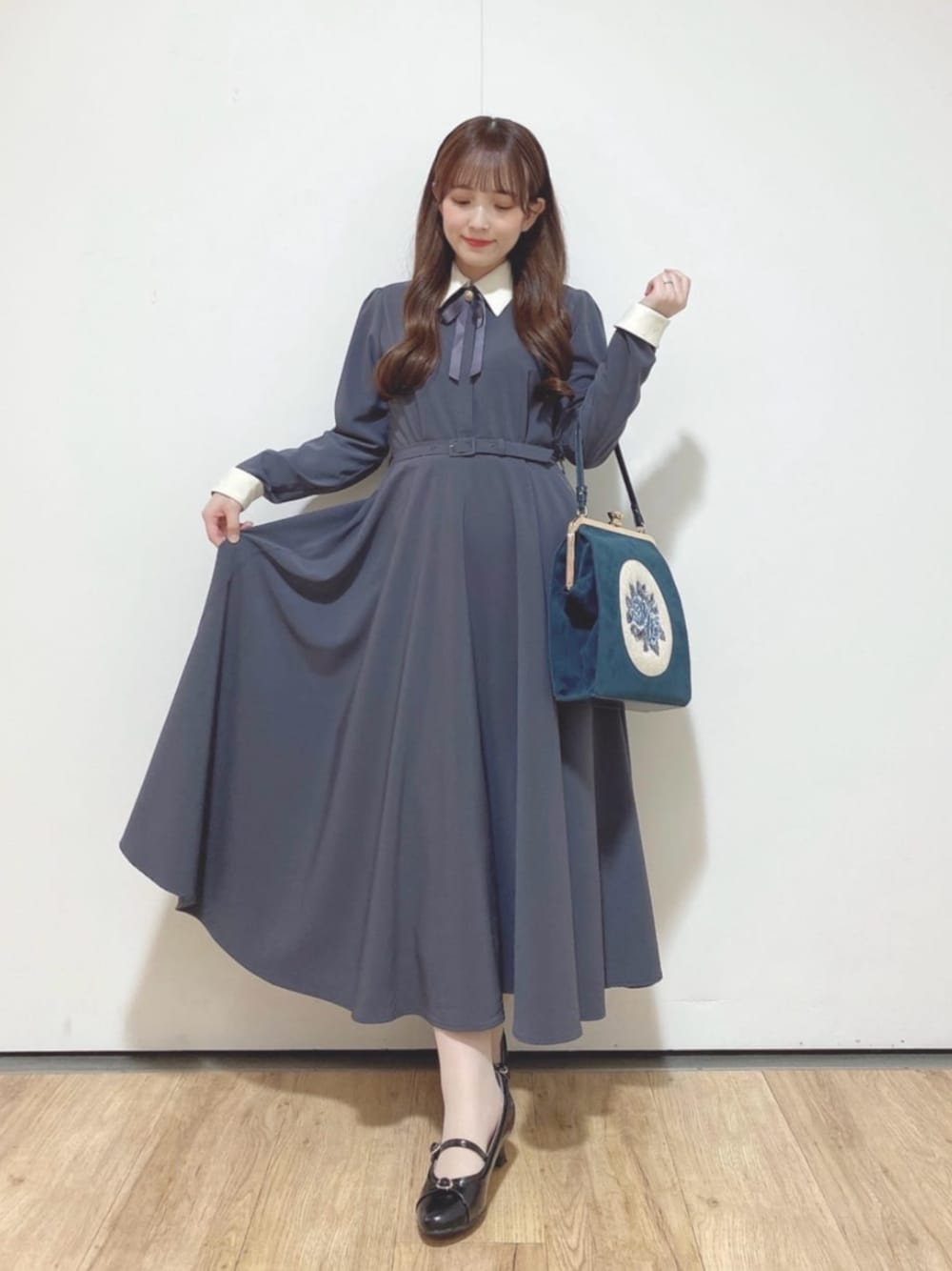ブラック系のパンプス、グレー系のワンピース、ブルー系のハンドバッグを着用したレディースの秋コーディネートの1枚目の写真