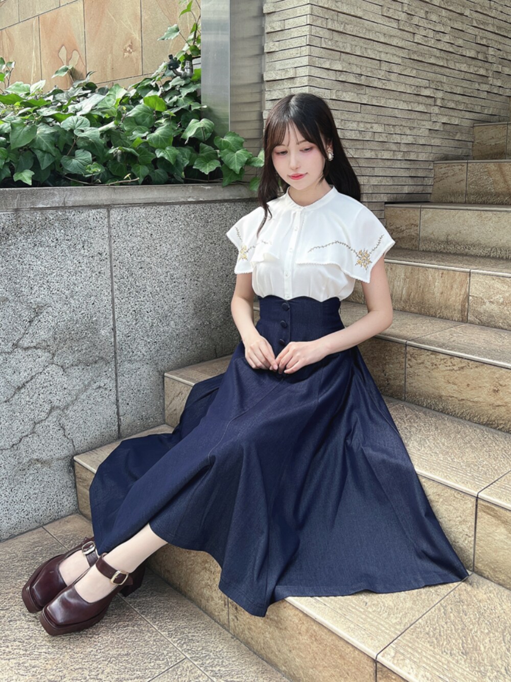 ブラウン系のパンプス、ホワイト系のシャツ/ブラウス、ブルー系のデニムスカートを着用したレディースの夏コーディネートの1枚目の写真