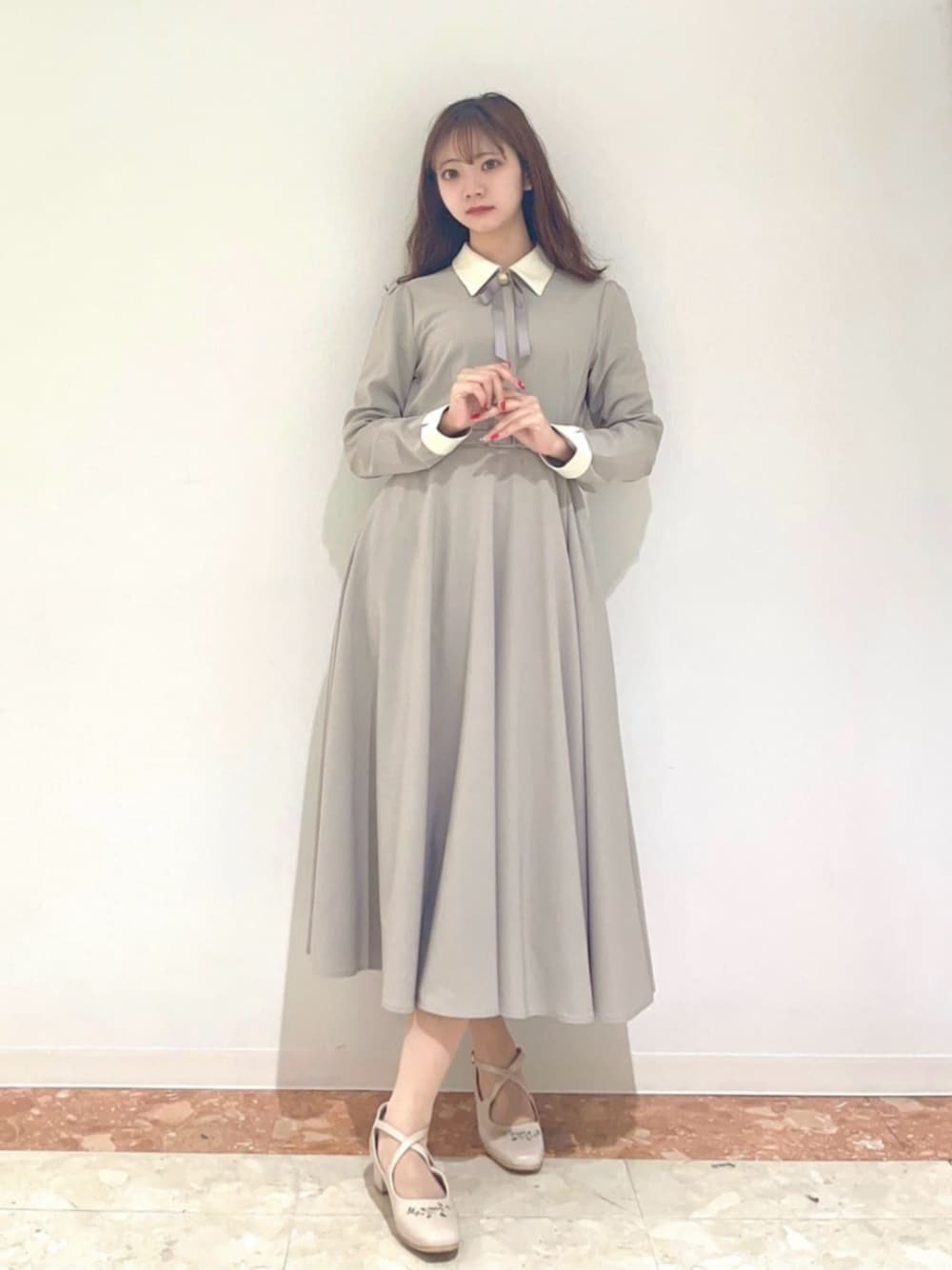 グレー系のワンピース、ホワイト系のパンプスを着用したレディースの秋コーディネートの1枚目の写真