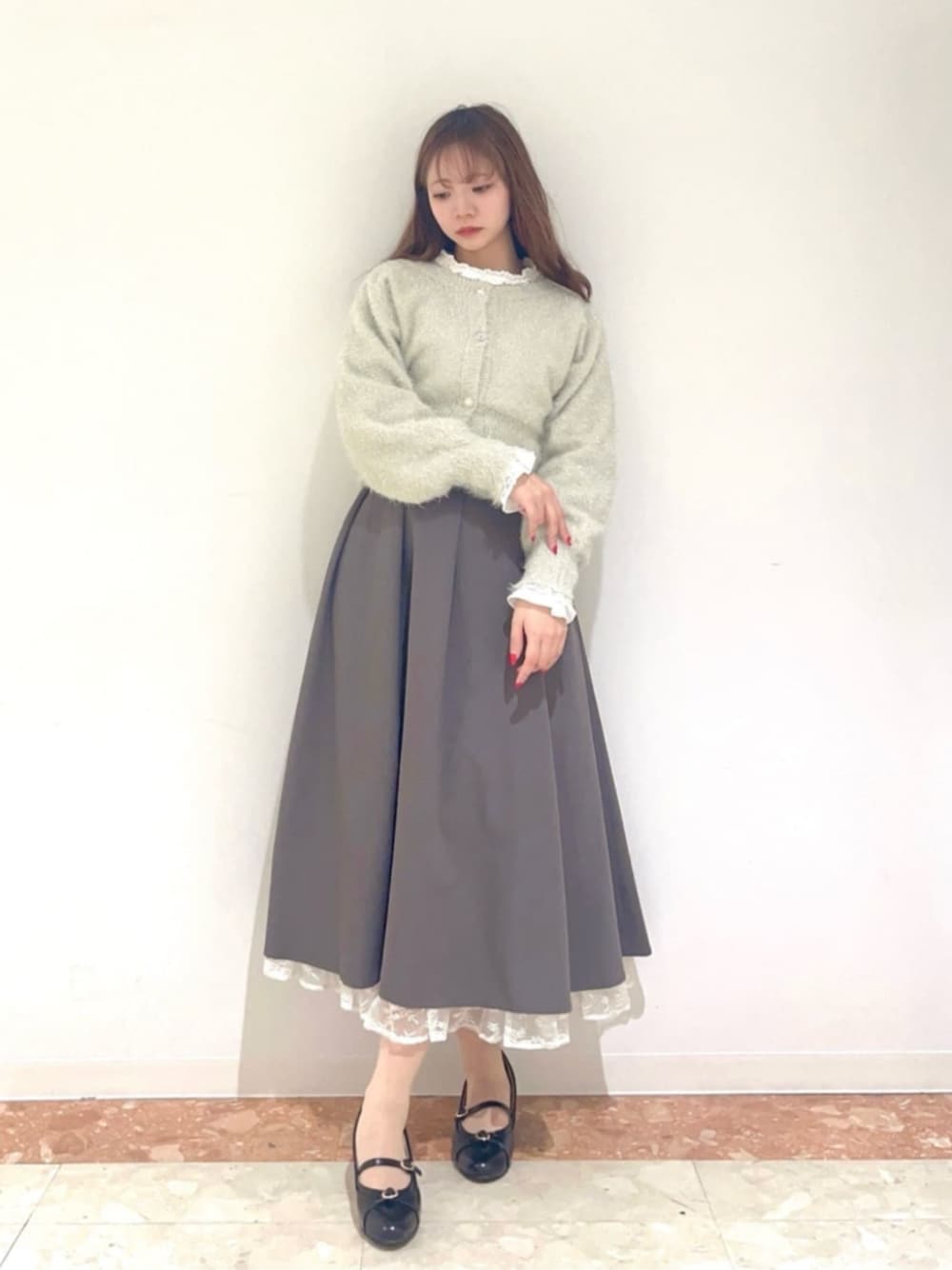 ブラック系のパンプス、ホワイト系のカーディガン/ボレロ、グレー系のスカートを着用したレディースの秋コーディネートの1枚目の写真