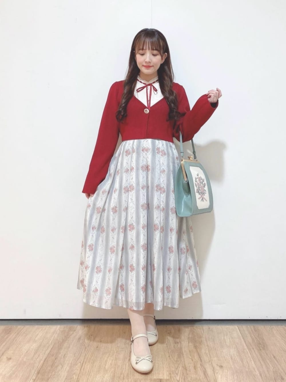 ベージュ系のパンプス、ピンク系のシャツ/ブラウス、グリーン系のスカートを着用したレディースの冬コーディネートの1枚目の写真