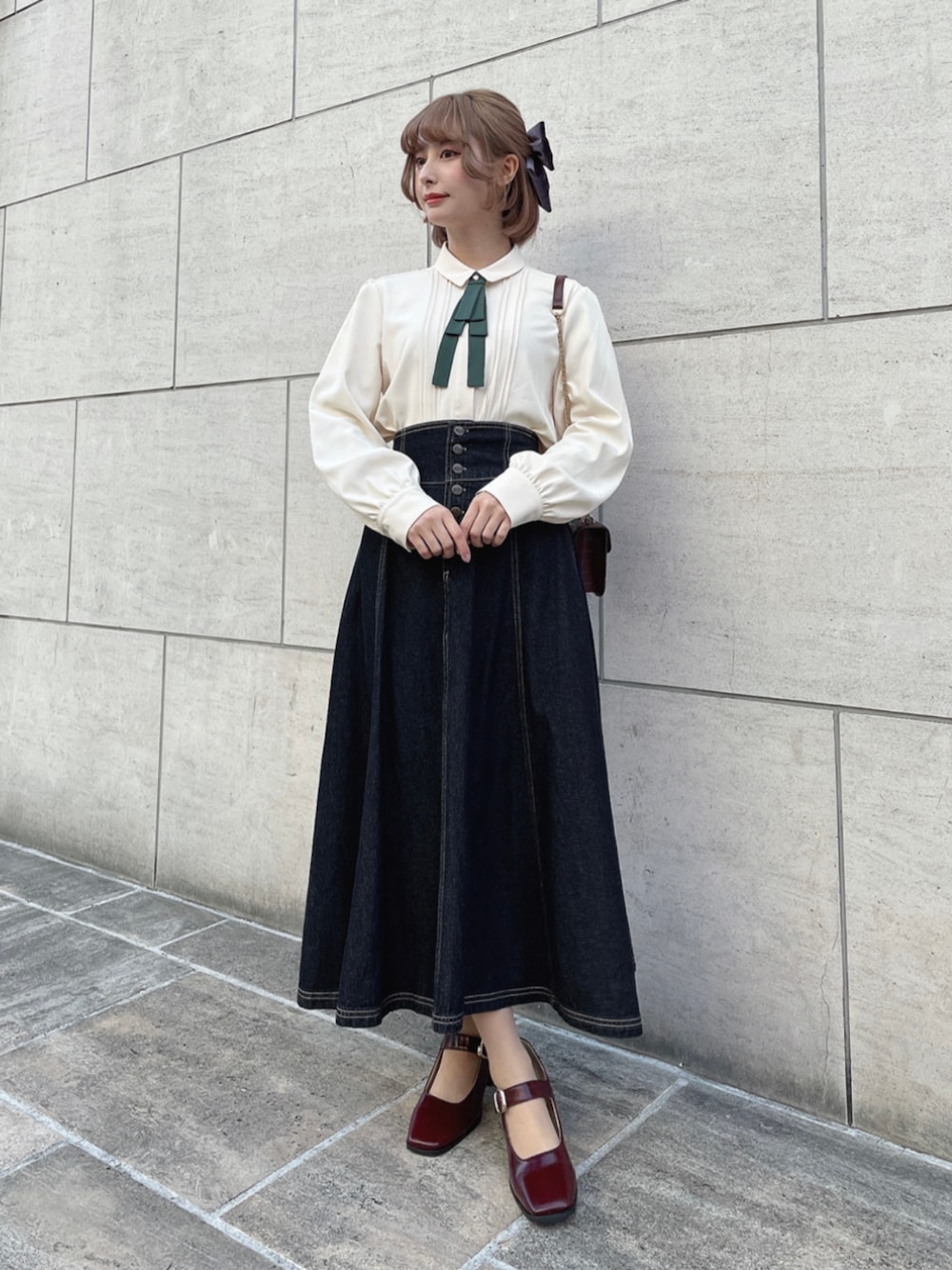 レッド系のパンプス、ブラック系のデニムスカート、ホワイト系のシャツ/ブラウスを着用したレディースの冬コーディネートの1枚目の写真