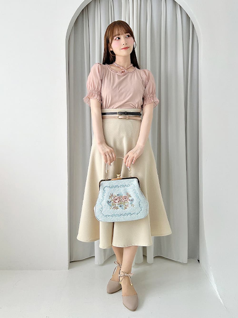 ベージュ系のスカート、ピンク系のパンプス、ブルー系のハンドバッグを着用したレディースの夏コーディネートの1枚目の写真