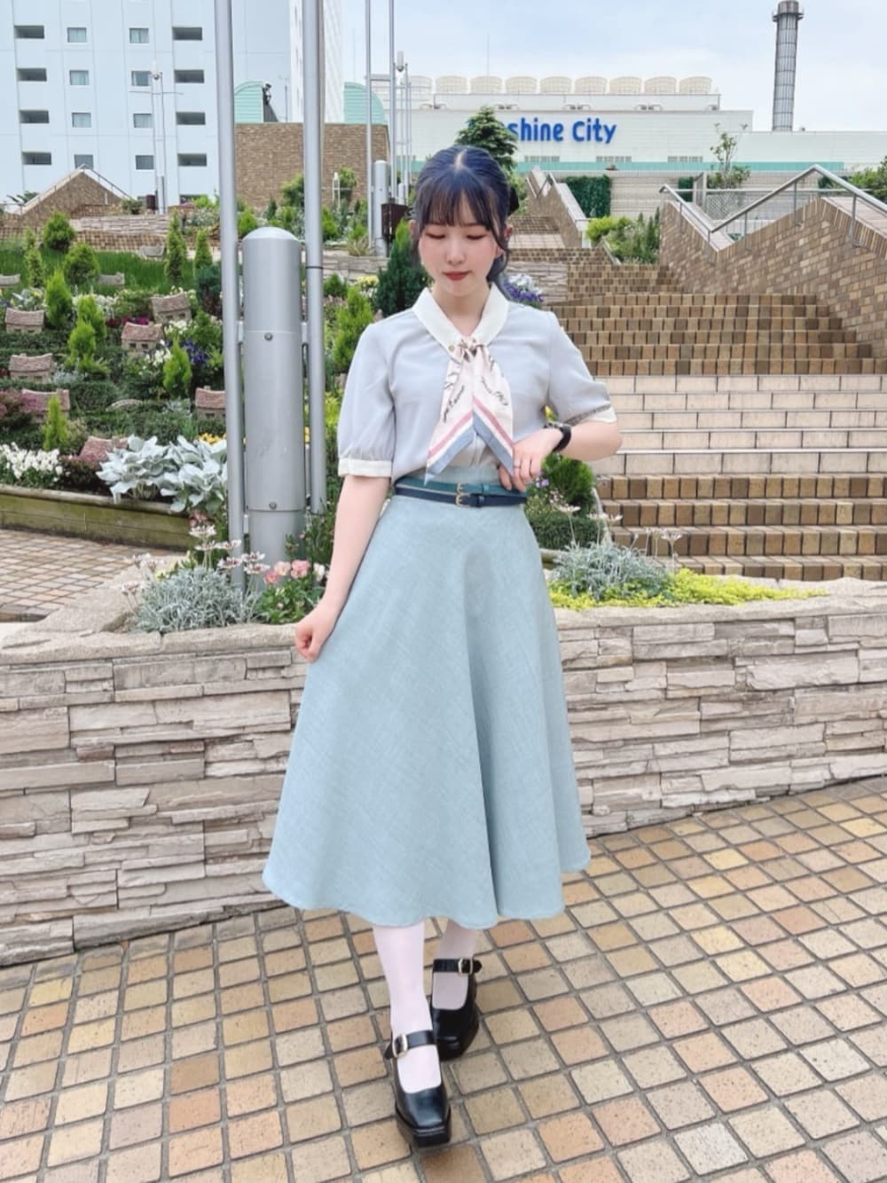 ブルー系のスカート、グリーン系のシャツ/ブラウス、ブラック系のパンプスを着用したレディースの夏コーディネートの1枚目の写真