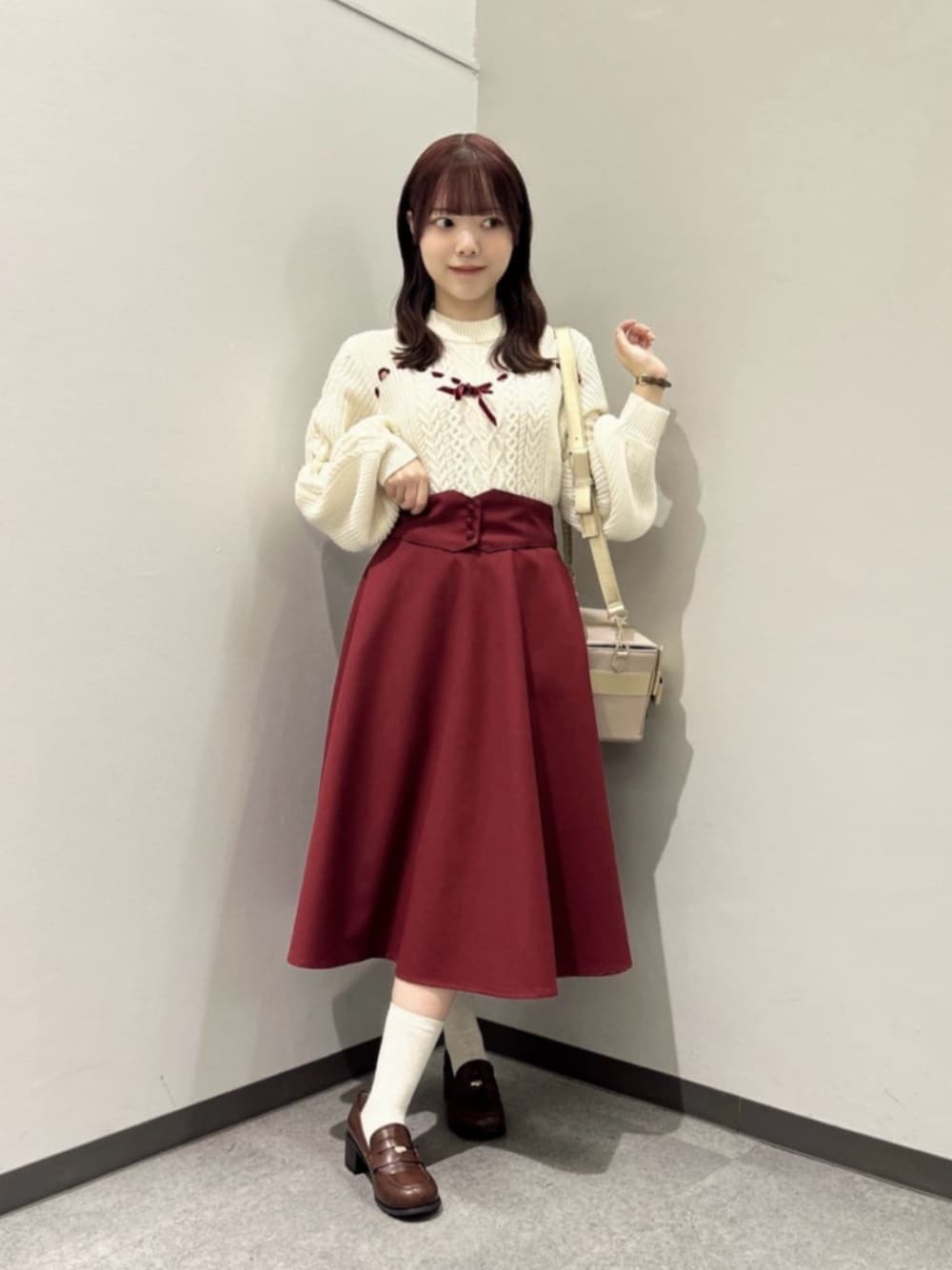 ブラウン系のローファー、レッド系のスカート、ホワイト系のニット/セーターを着用したレディースの秋コーディネートの1枚目の写真