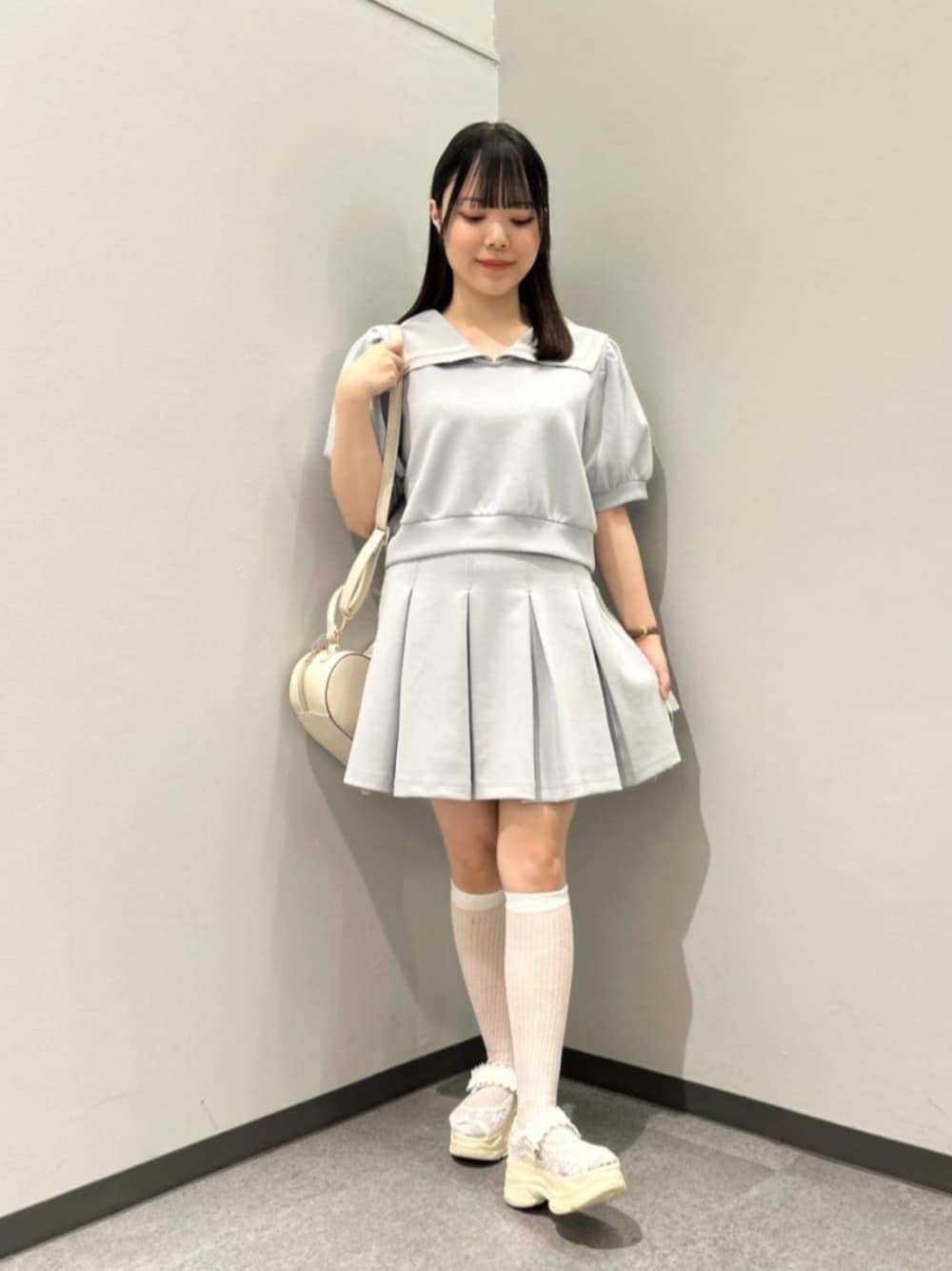 ブルー系のスカート、ホワイト系のハンドバッグ、ホワイト系のサンダルを着用したレディースの夏コーディネートの1枚目の写真